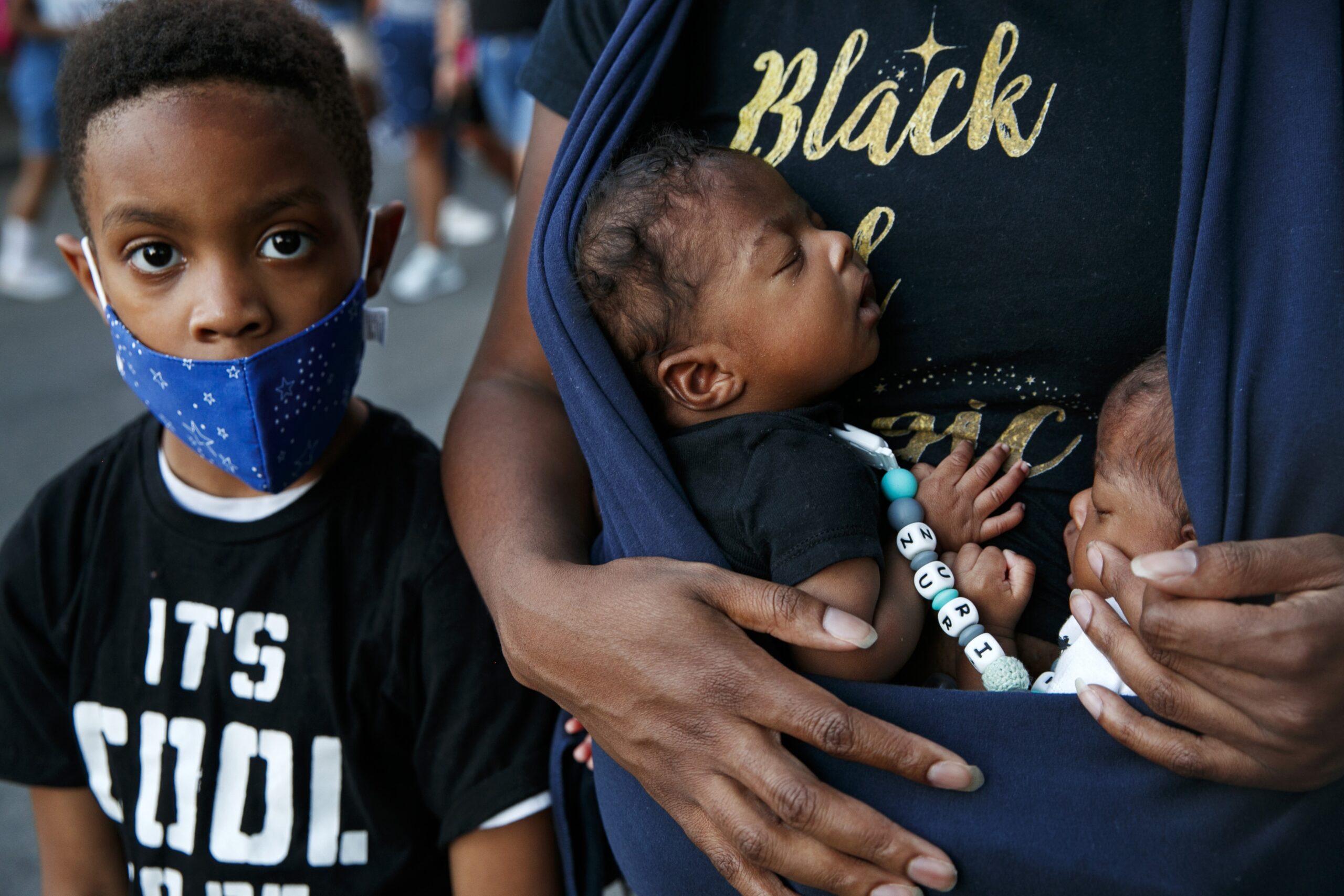 Xavier Simmorins stands next to his brothers, 8-week-old twins Zuri and Zakai Simmorins, as they are held by their mother Samara Simmorins, during a protest