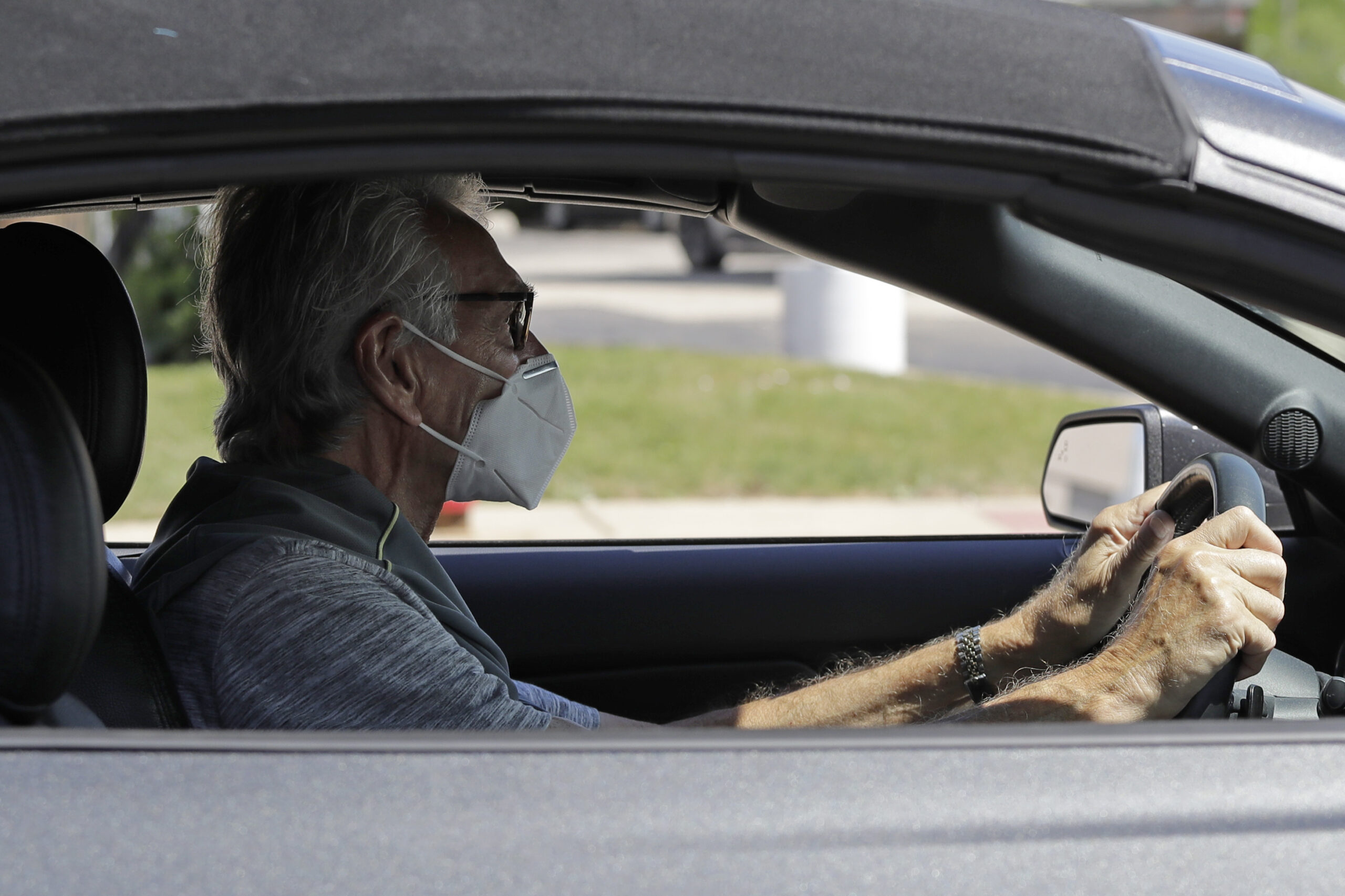 A man wears a mask while he is driving in Deerfield, Ill.