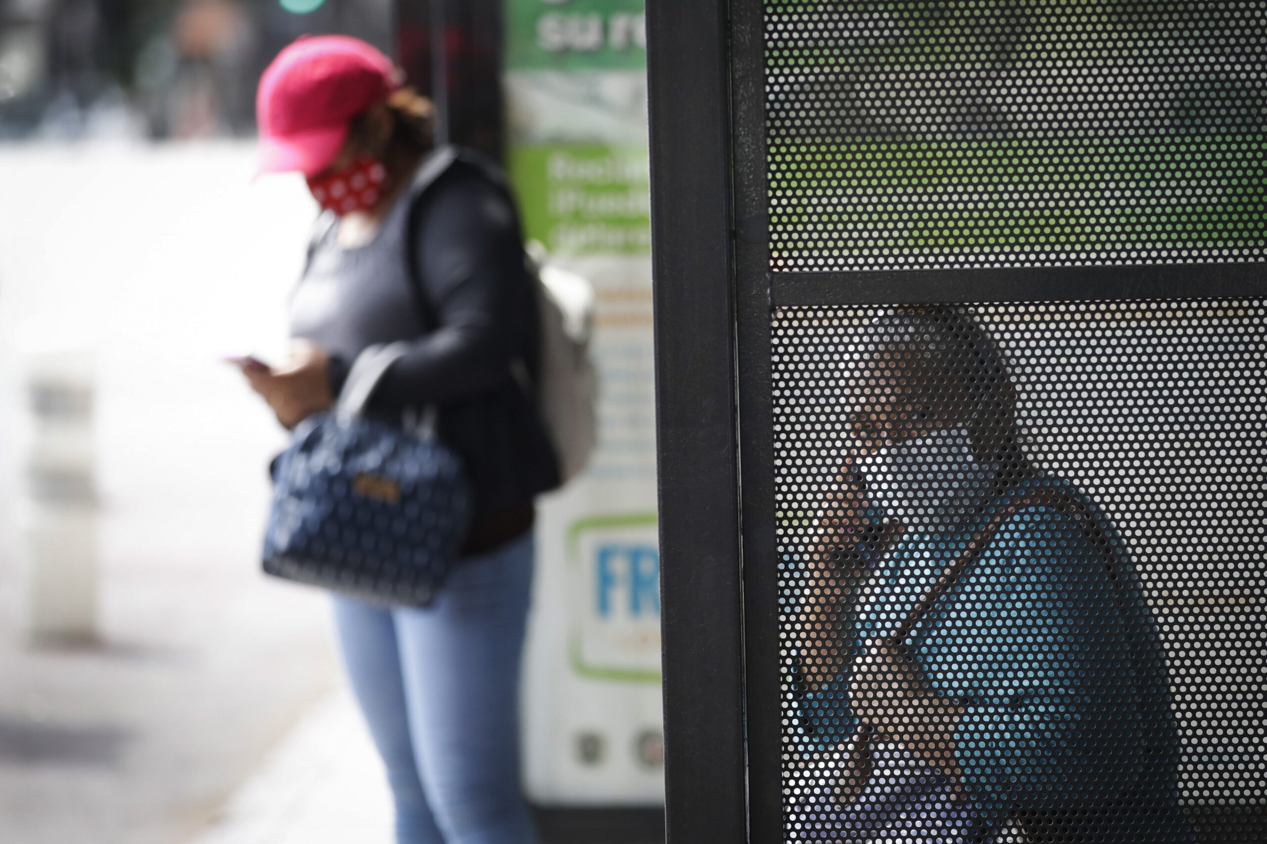 Two women wait at a bus stop amid the coronavirus pandemic
