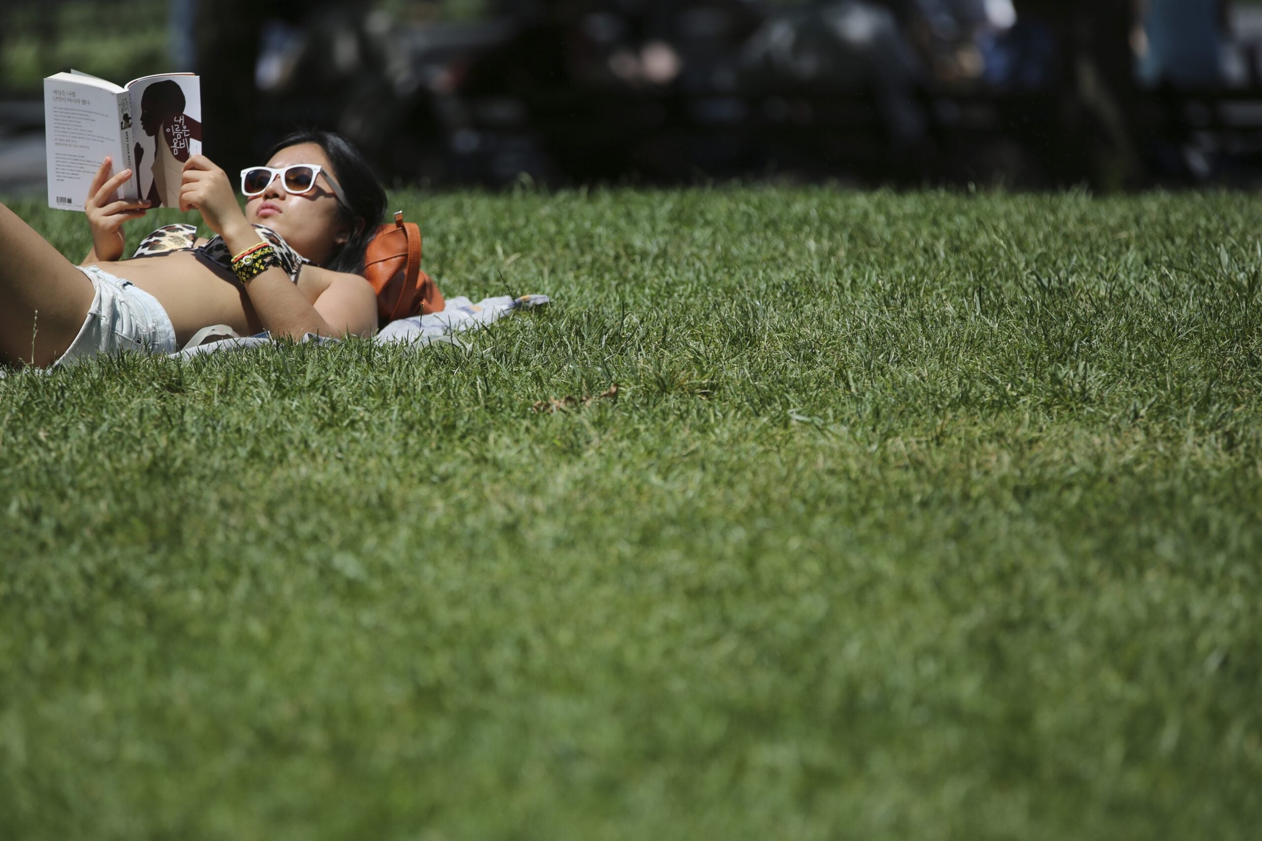 A woman reads a book while sunbathing