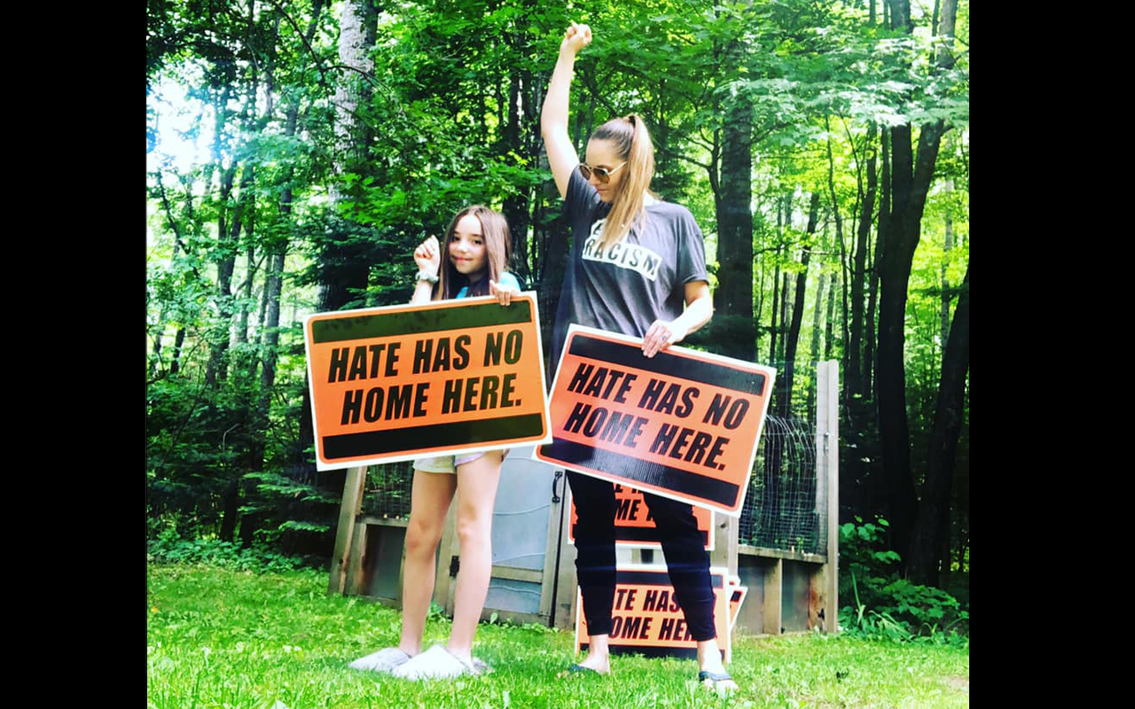 Chelsea Romaker and her daughter Eliana display "Hate has no home here" signs