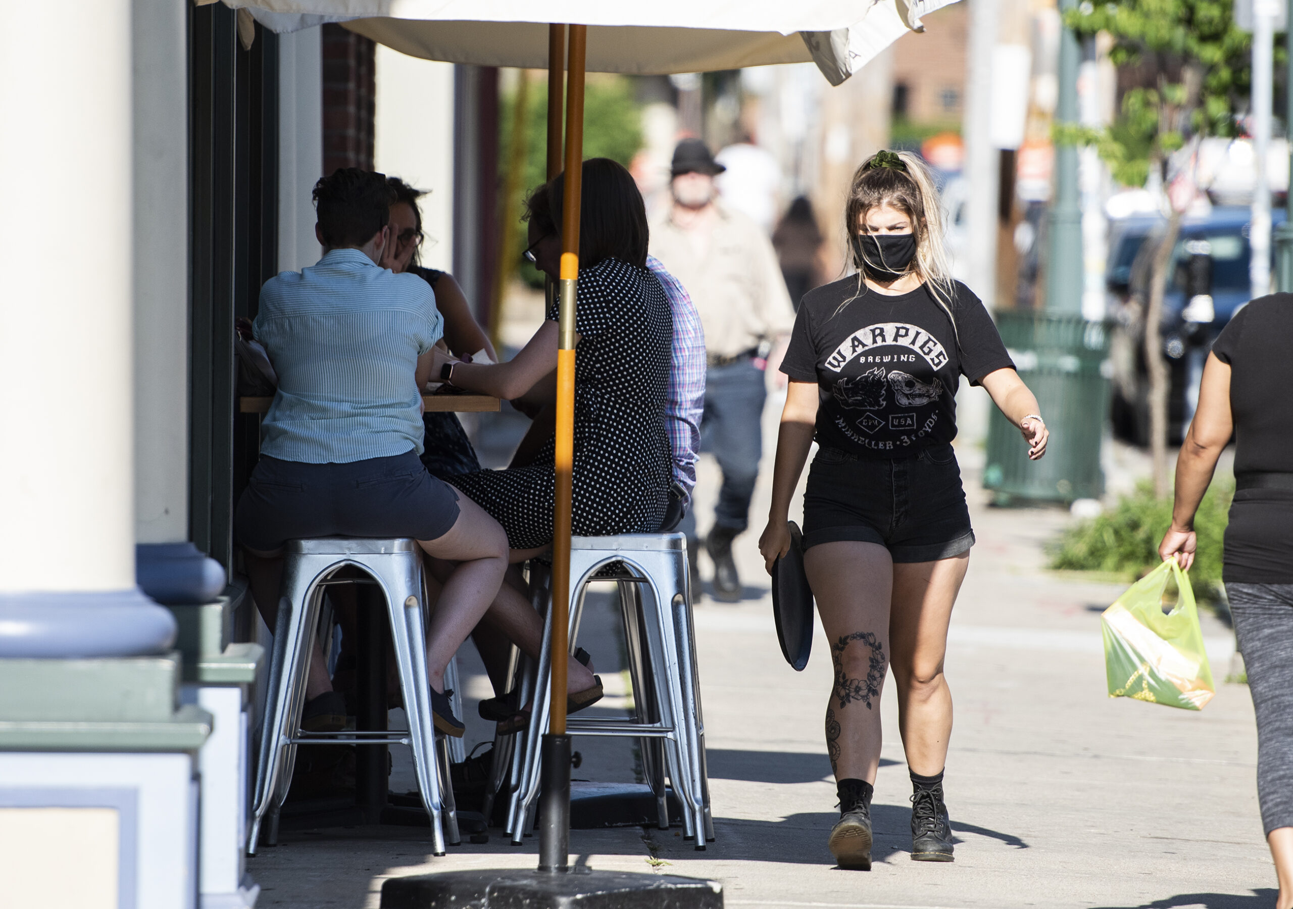 waitress wears a mask while serving customers outside