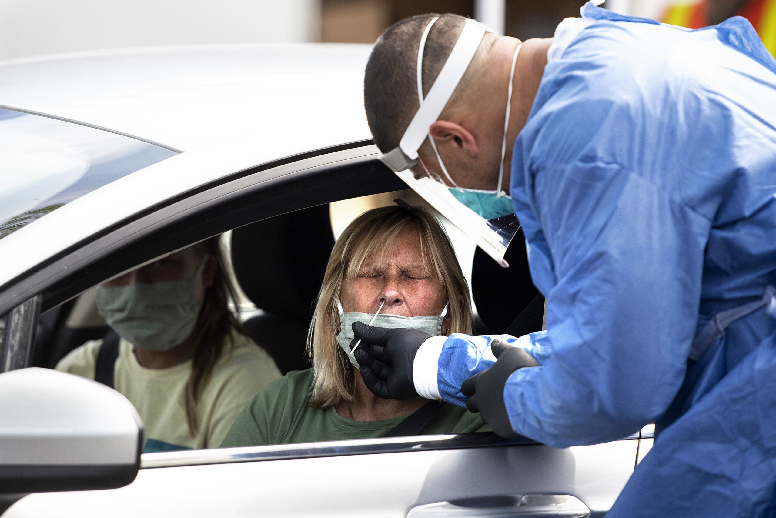 A woman's nose is swabbed while receiving a COVID-19 test at a drive thru location