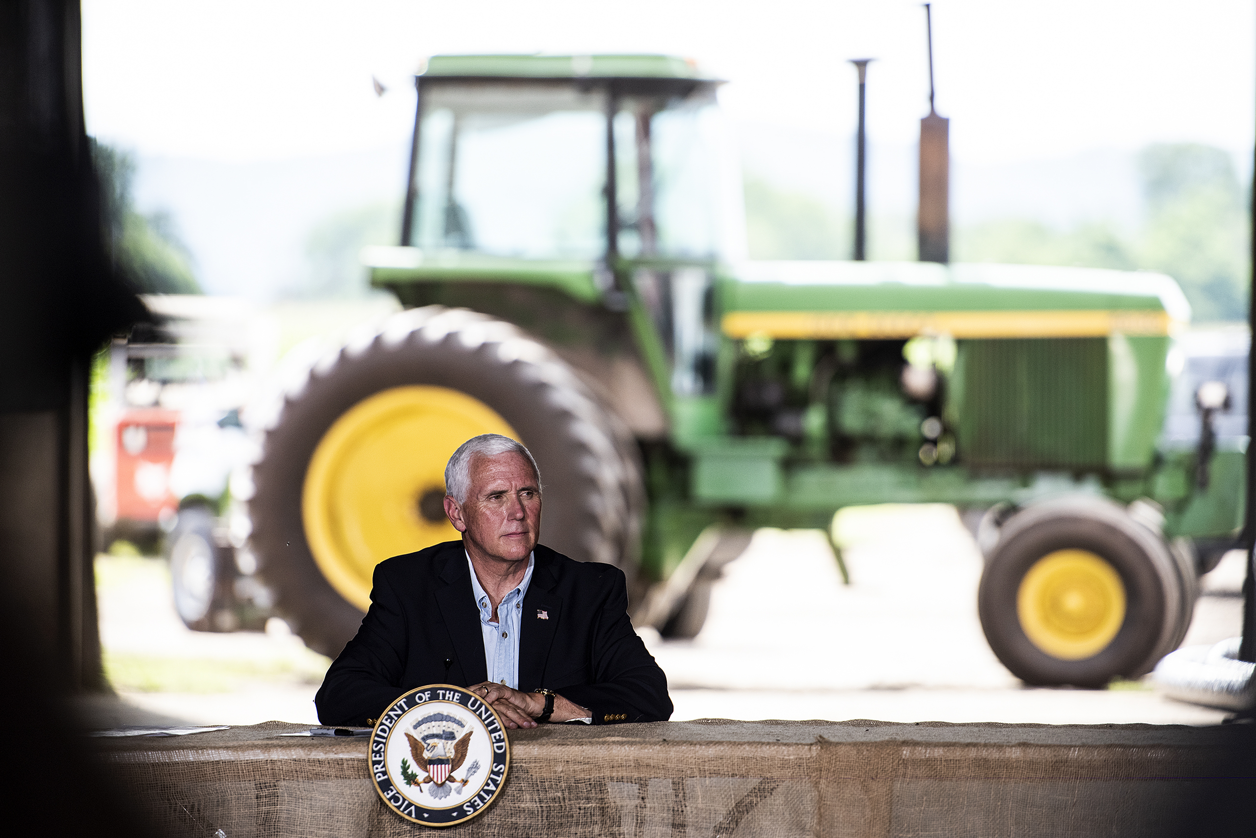 Vice President Mike Pence sits at a roundtable with a tractor in the background