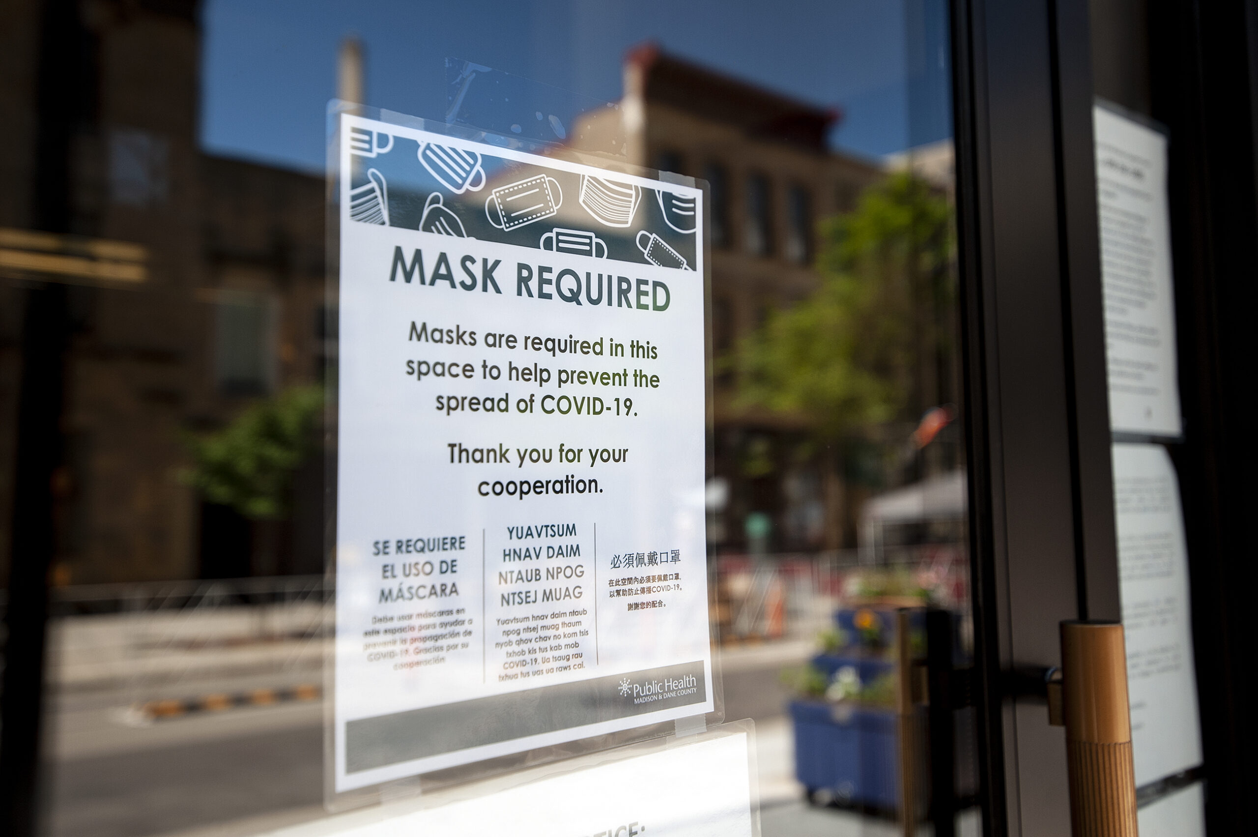 A sign on a glass door says "mask required"