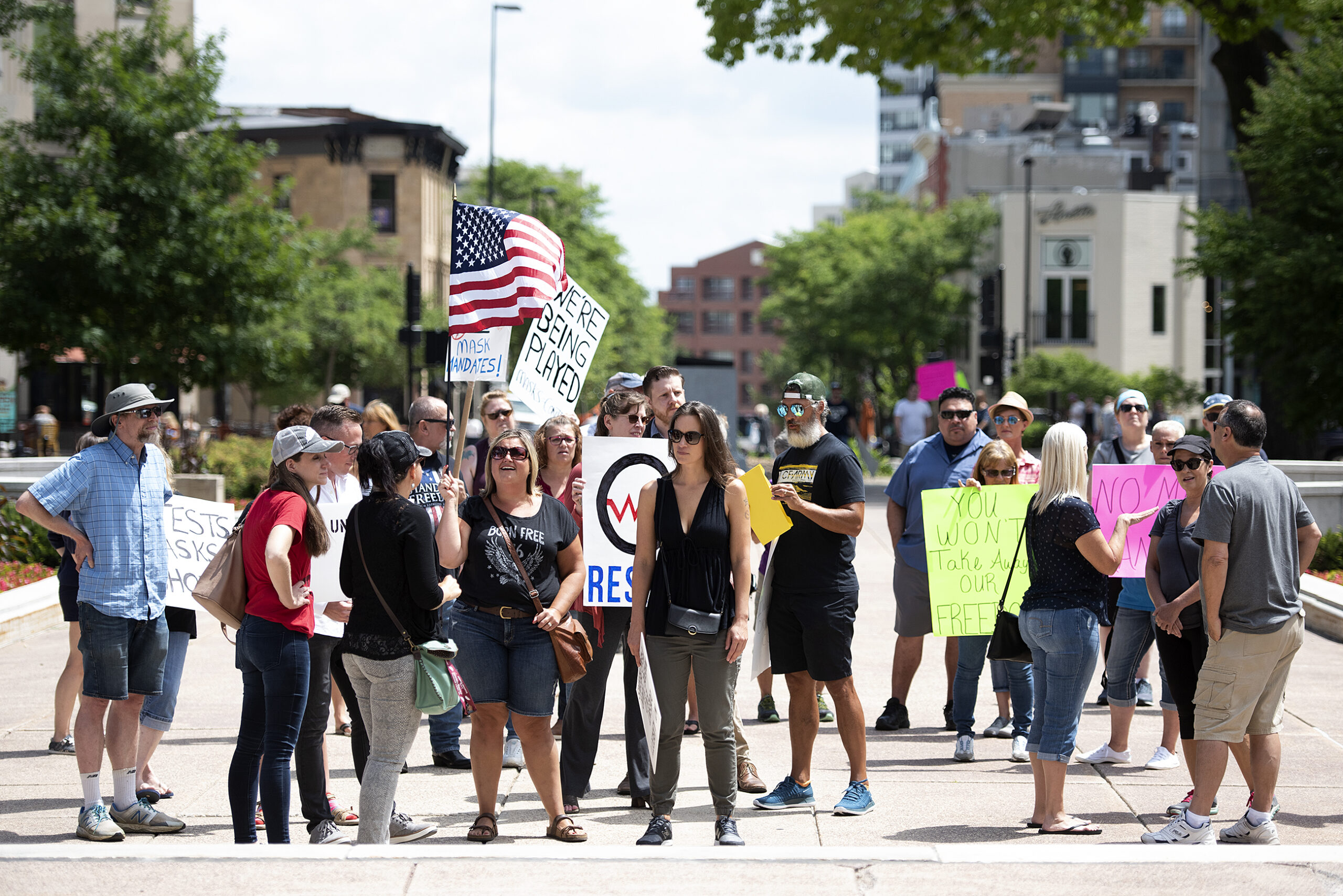 protesters hold signs and an American flag