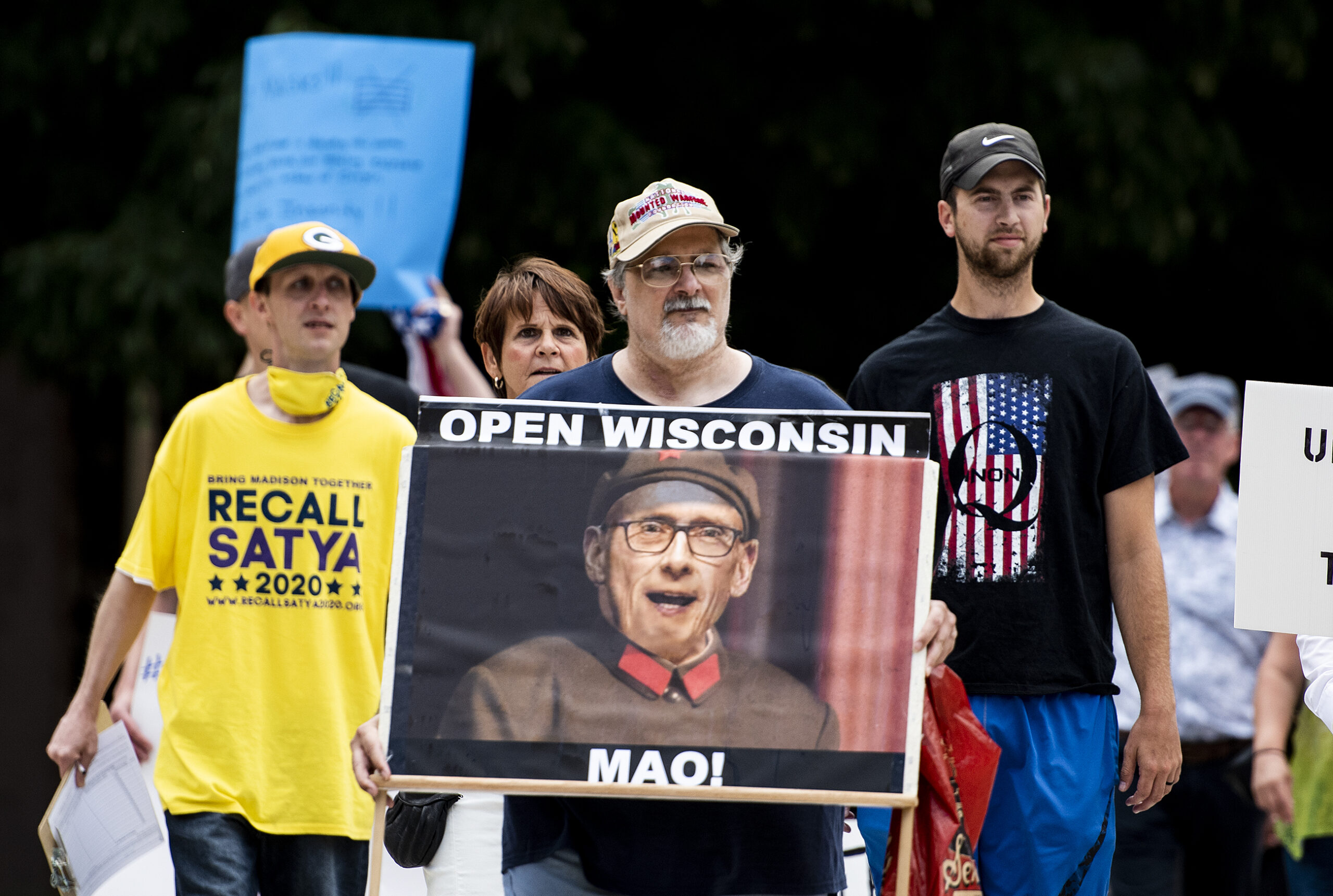 A man holds a sign that compares Gov. Evers to Mao