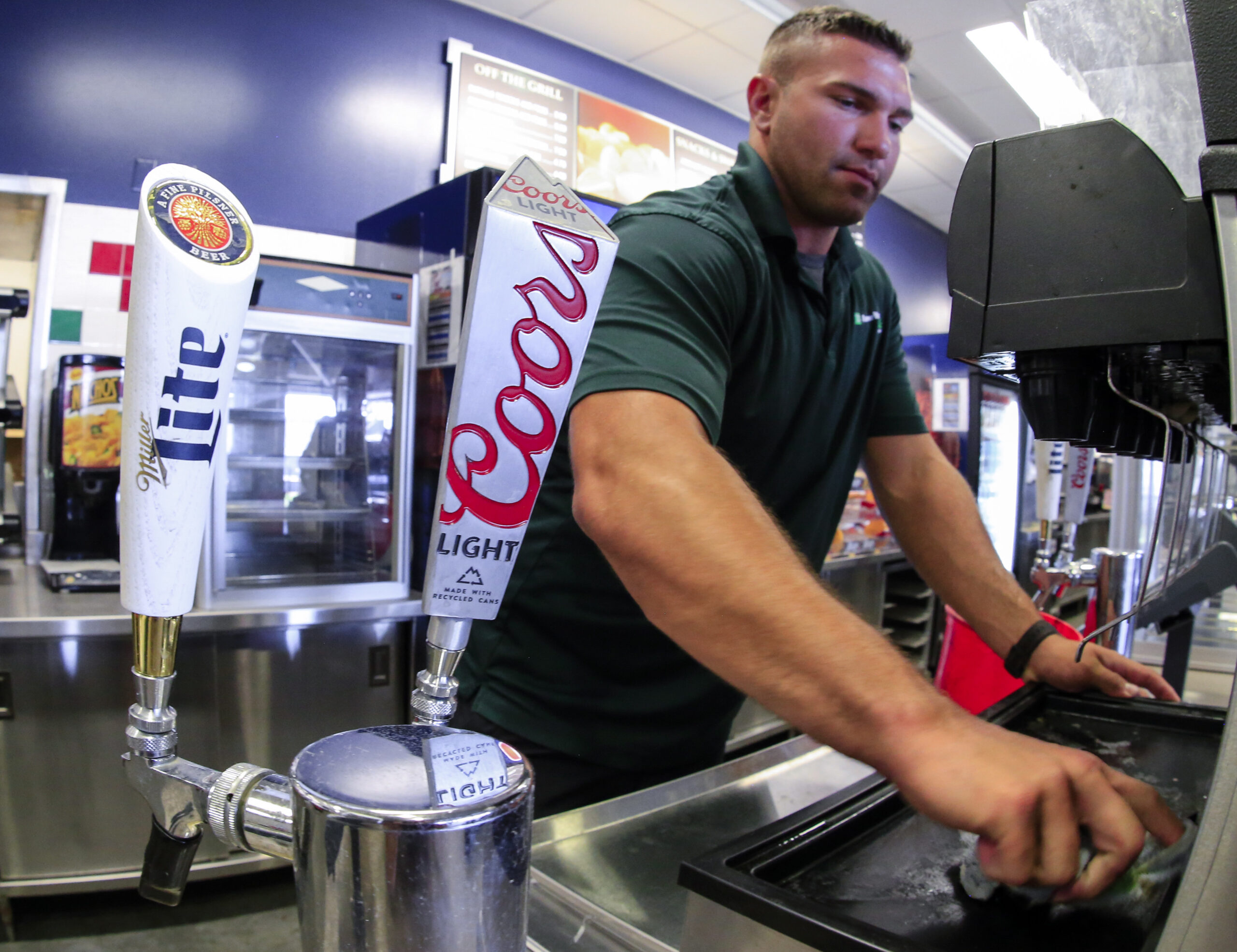Trevor Hilger cleans a concession stand next to beer taps