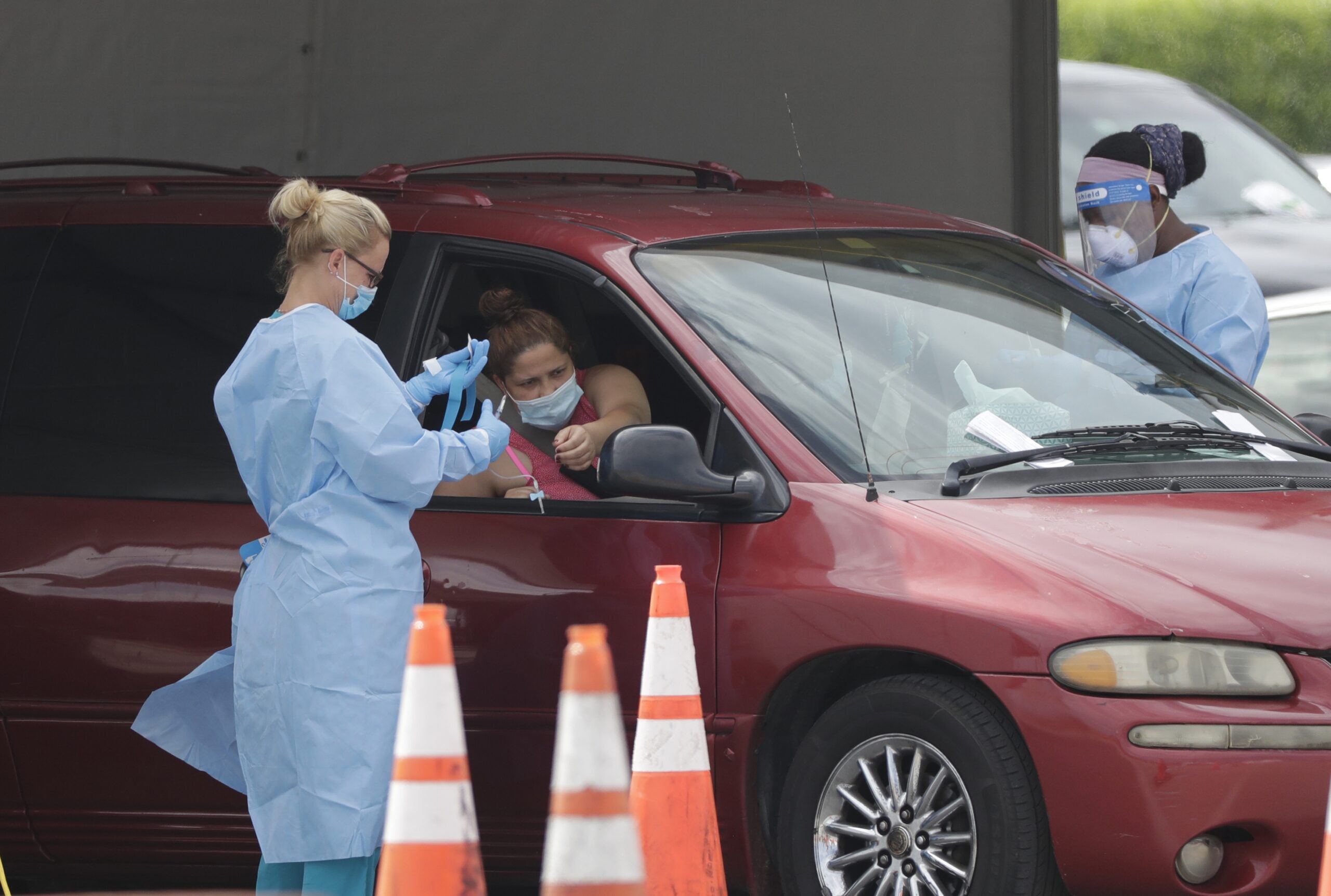 A healthcare worker prepares to draw blood at a drive-through coronavirus testing site.