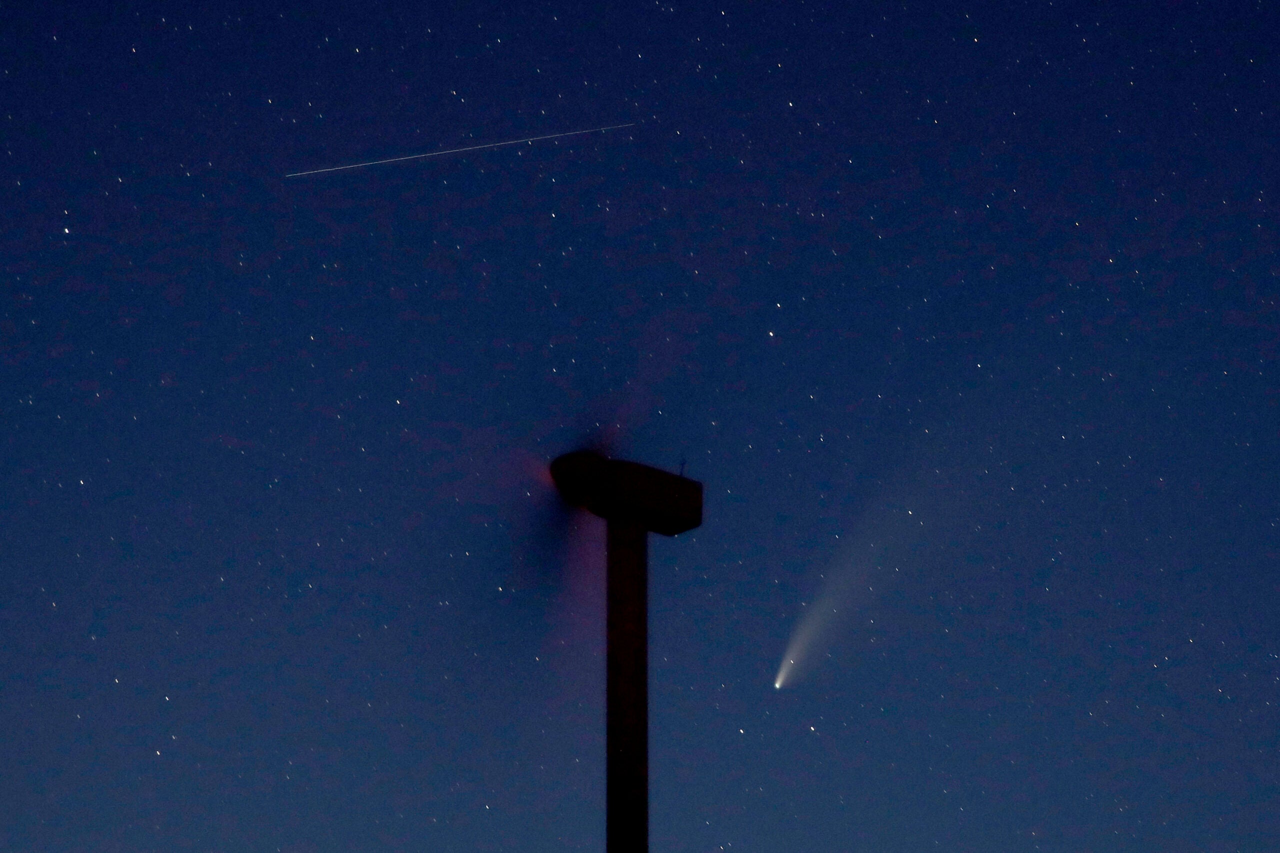 The comet Neowise, below, is seen in the night sky beyond a wind turbine
