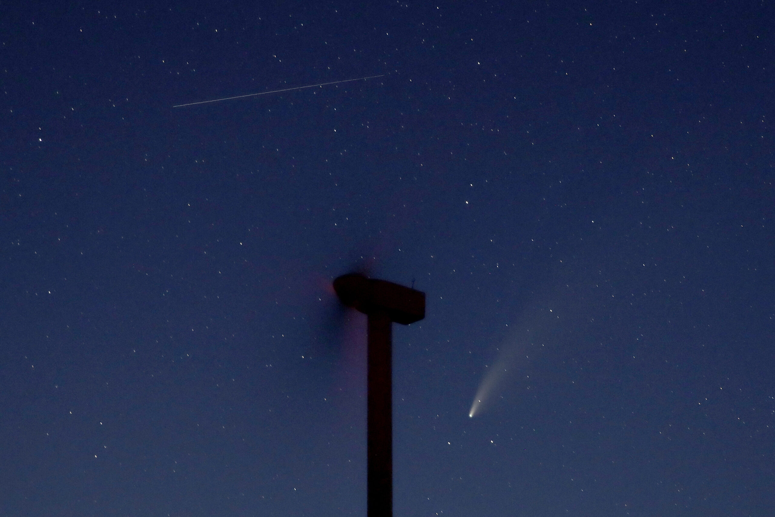 The comet Neowise, below, is seen in the night sky beyond a wind turbine