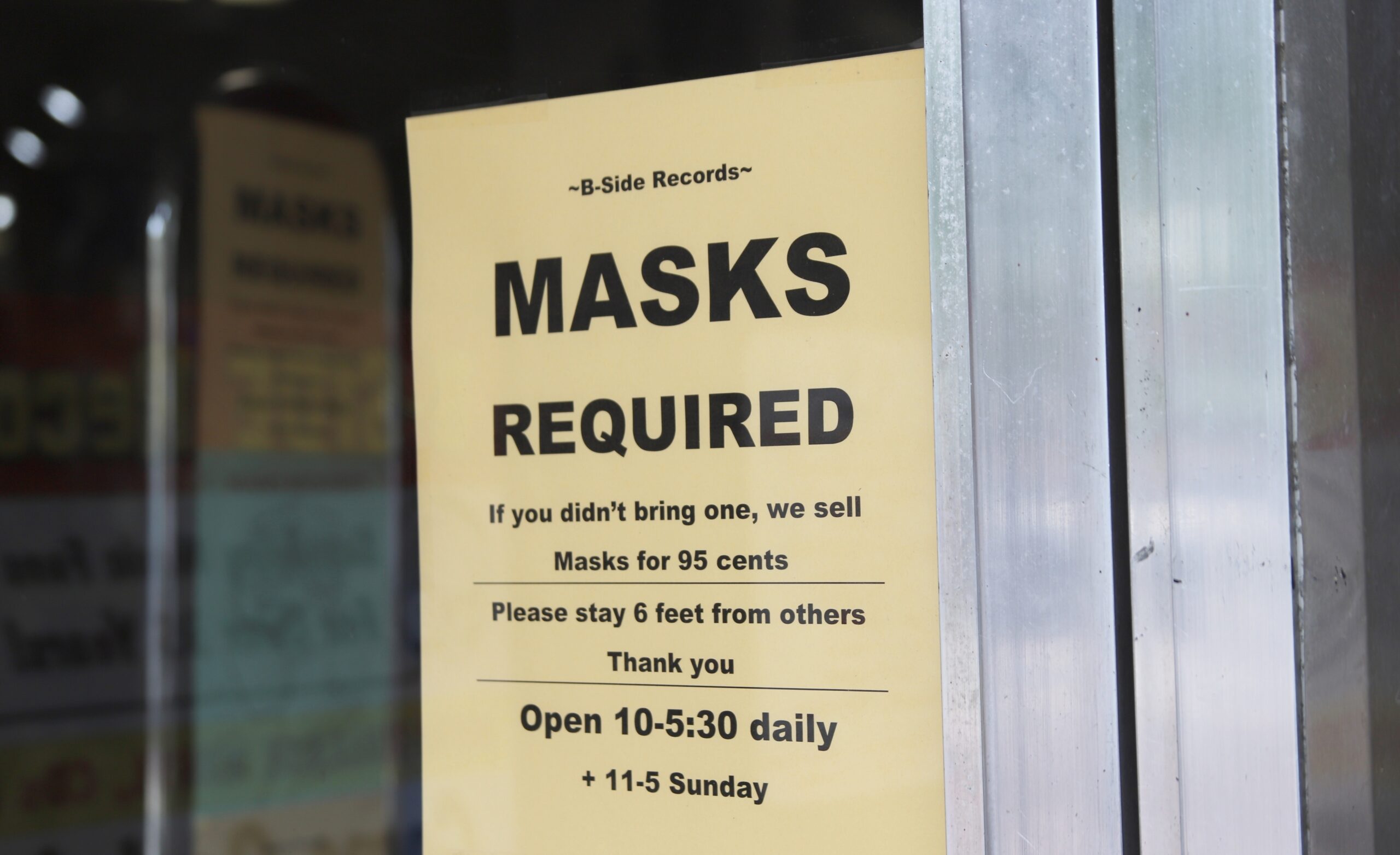 A sign outside B-Side Records in Madison explains the store's mask policy