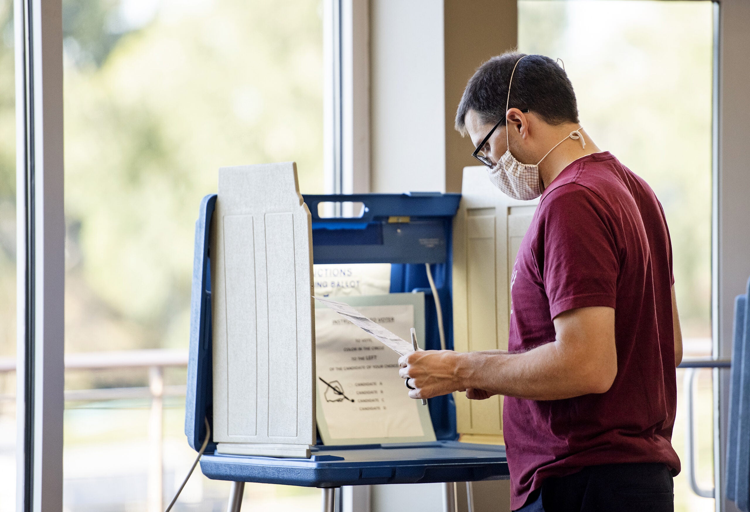 a man in a face mask holds a ballot