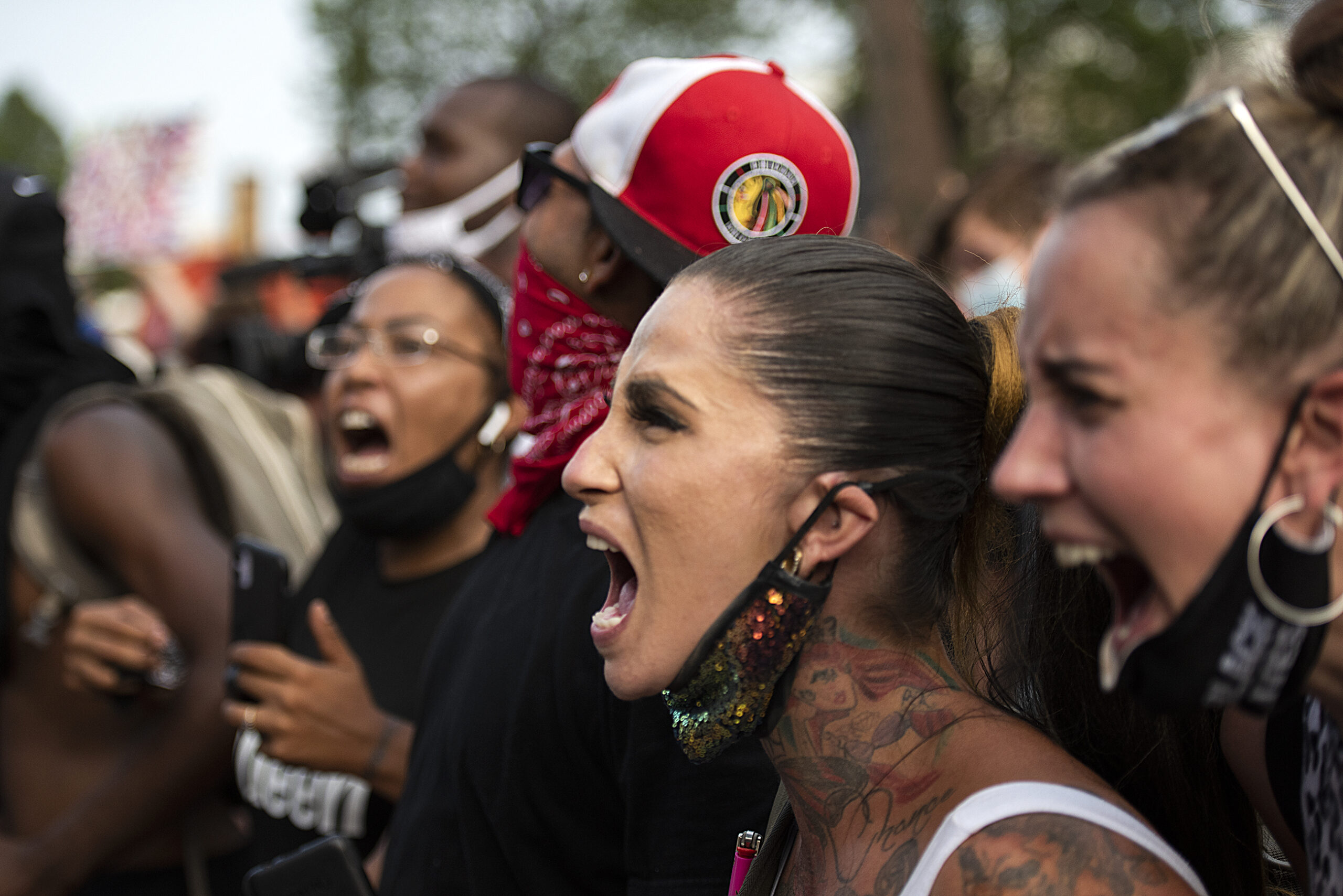 a woman with a mask pulled down to her neck yells with the crowd next to her