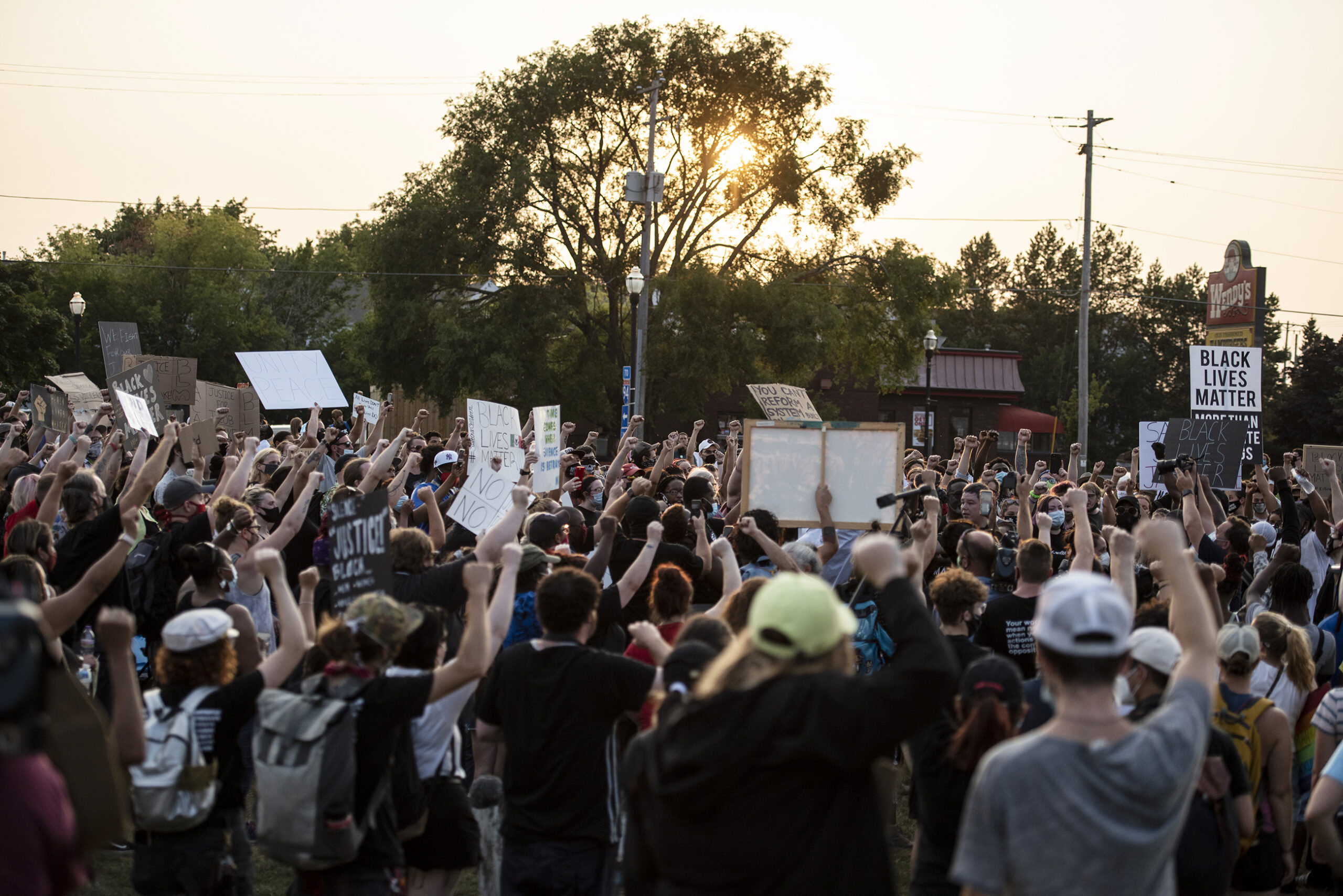 a sea of raised fists and signs take up a field in Kenosha