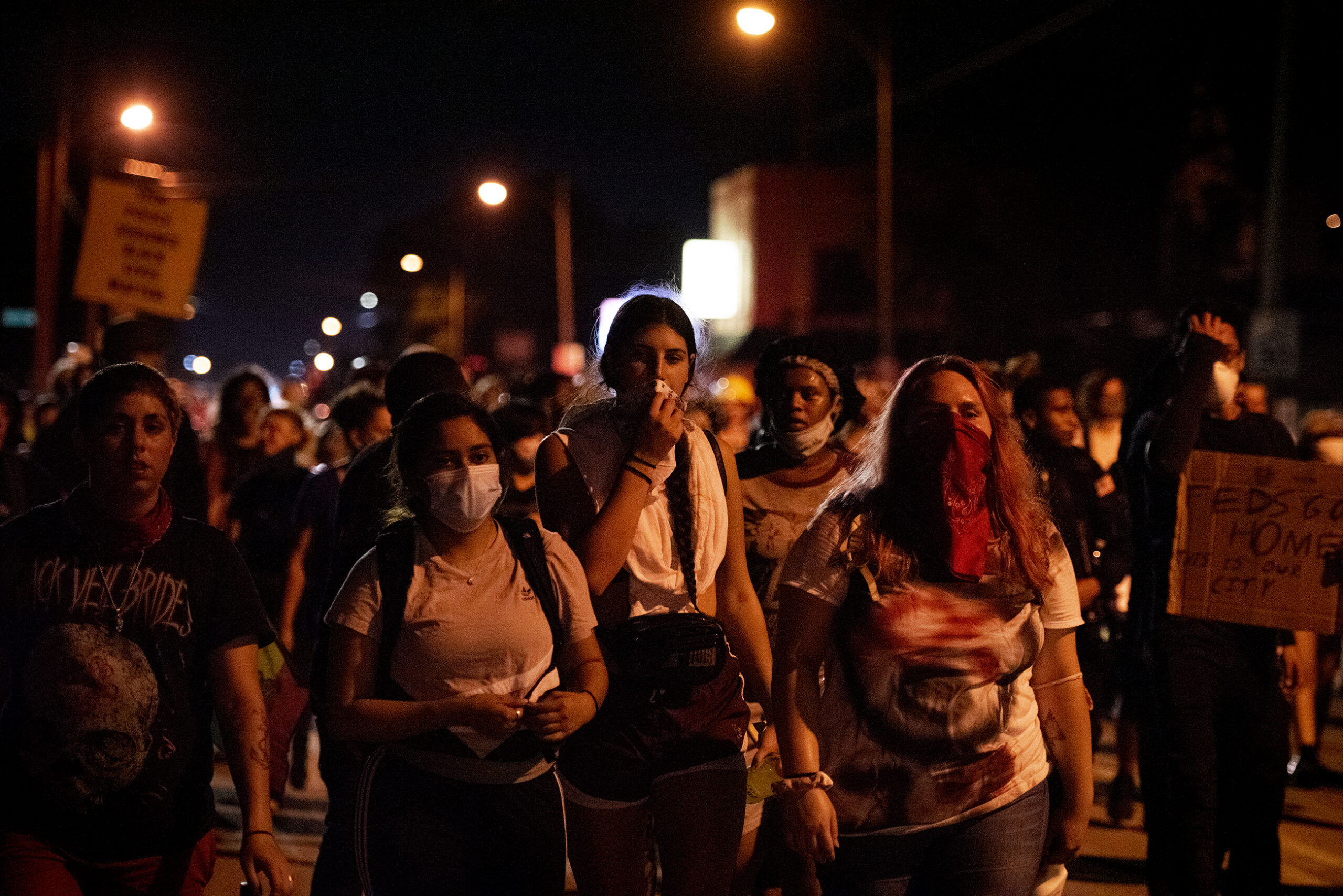 protesters march on a dark street illuminated by street lights