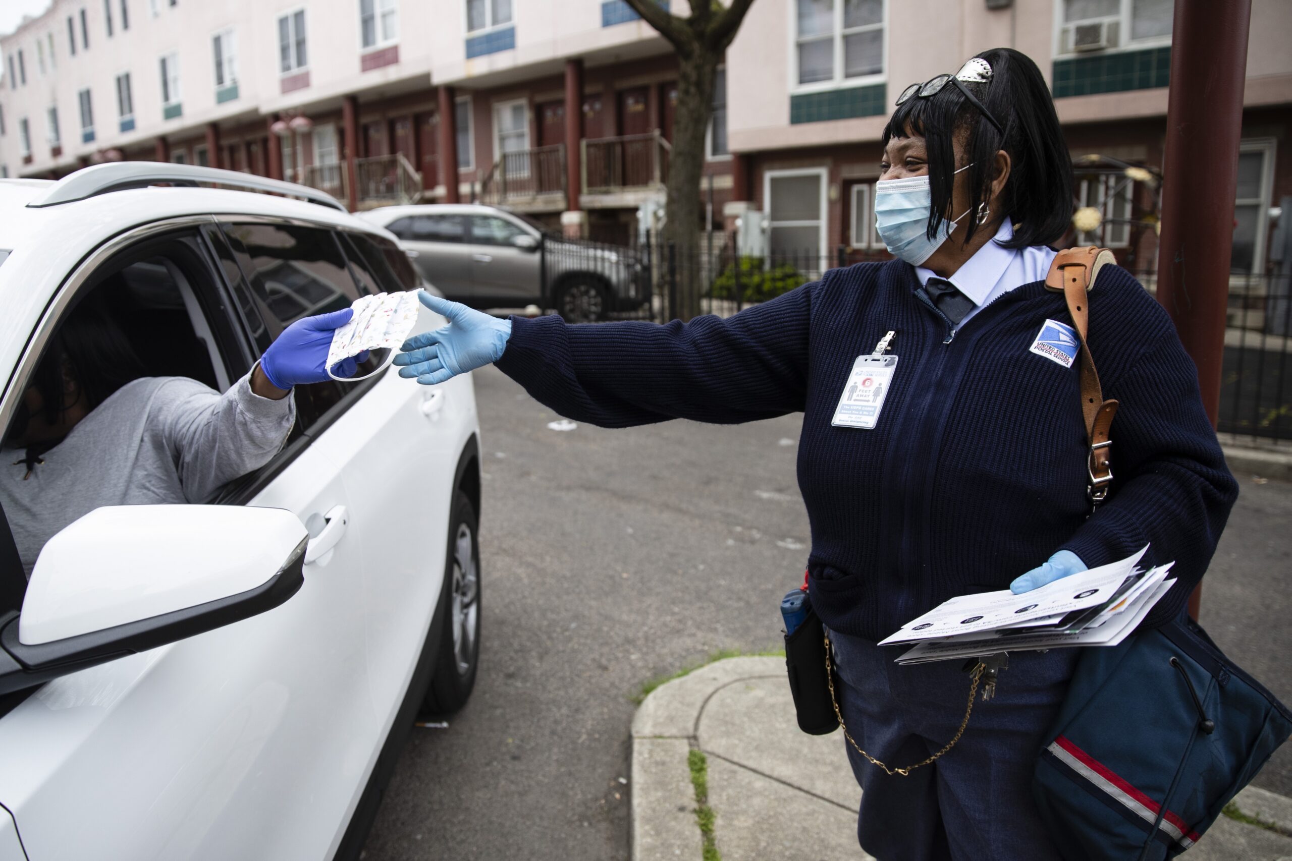 Esther Haynes, left, gives United States Postal Service carrier Henrietta Dixon a protective face mask as she delivers mail