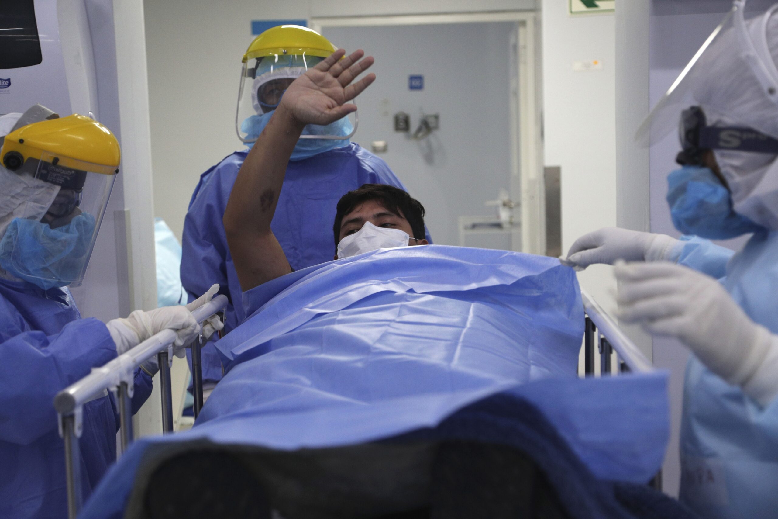 A patient waves goodbye to other patients as he is taken out of the intensive care unit for COVID-19 cases