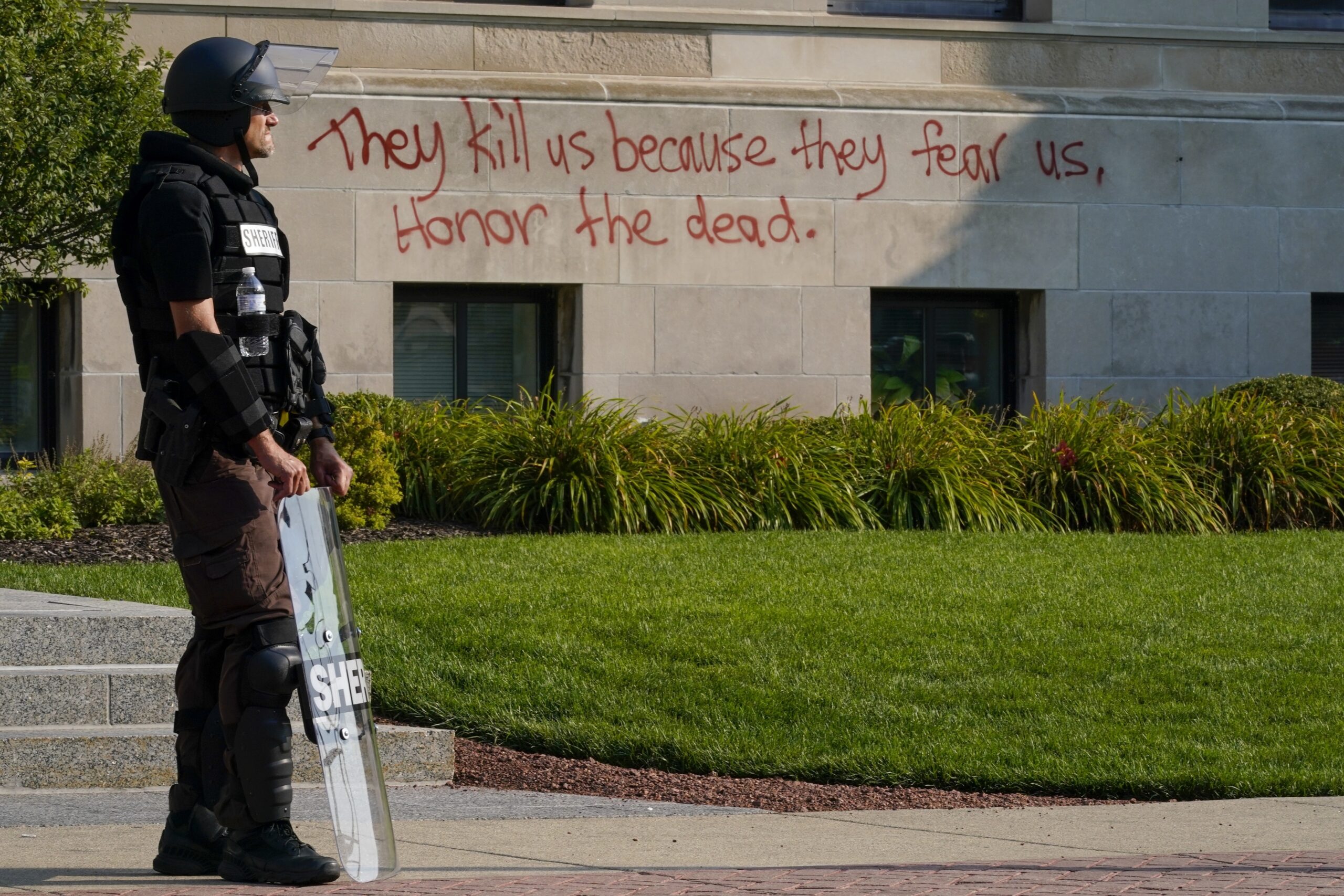 Police in riot gear stand outside the Kenosha County Court House Monday
