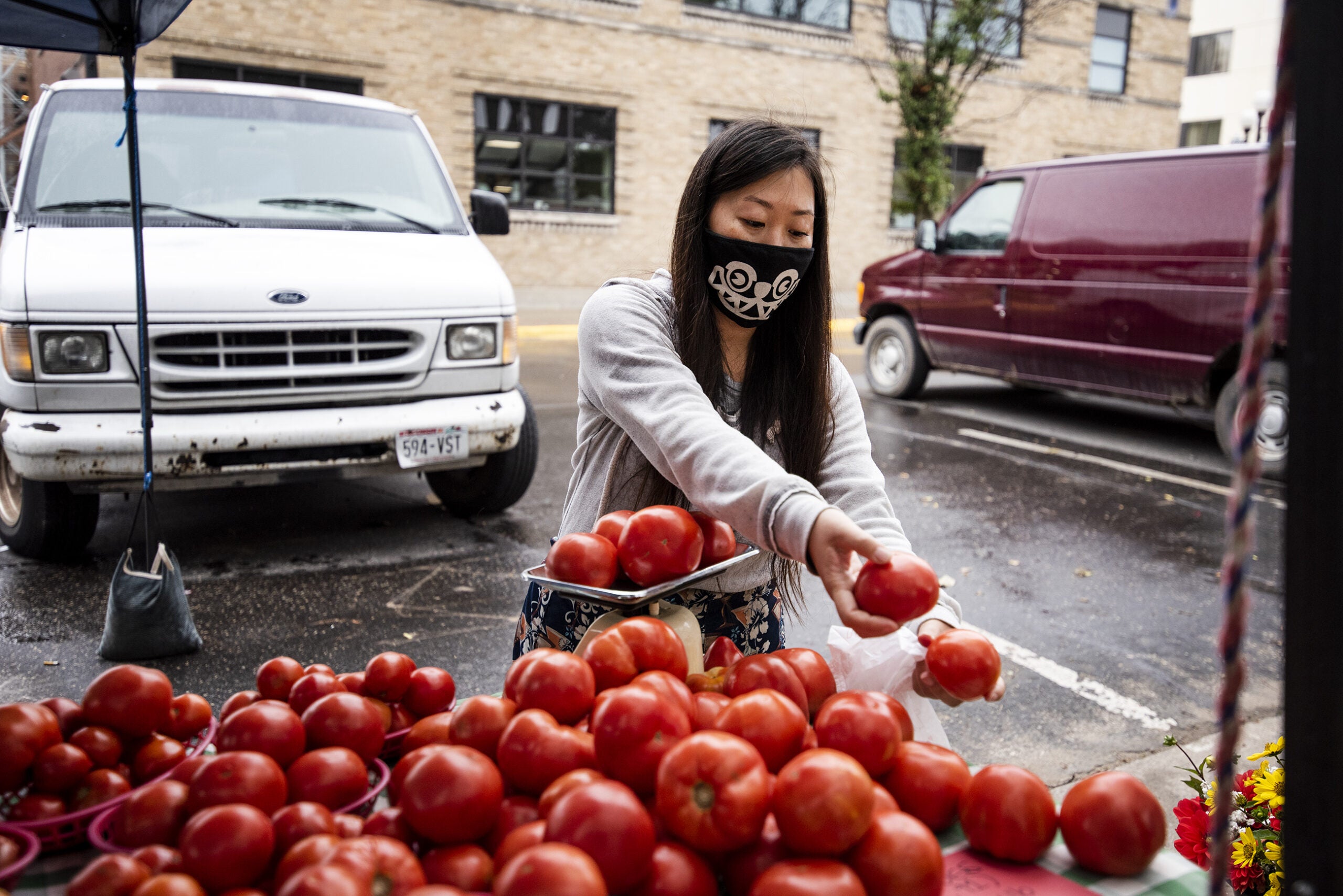 a woman places red tomatoes onto a small scale