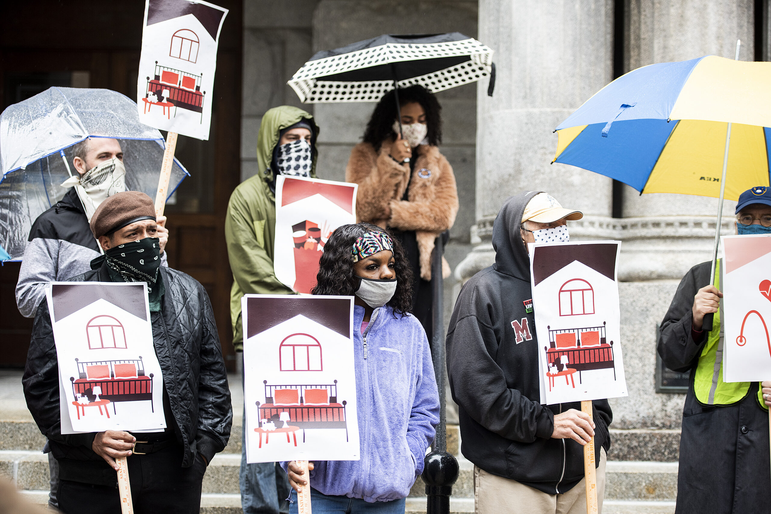 people hold signs as they listen to speakers