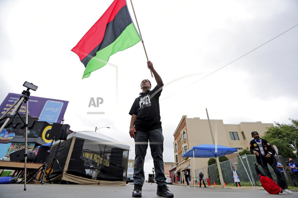 Duncan Ellington waves an African flag during a protest rally for Jacob Blake