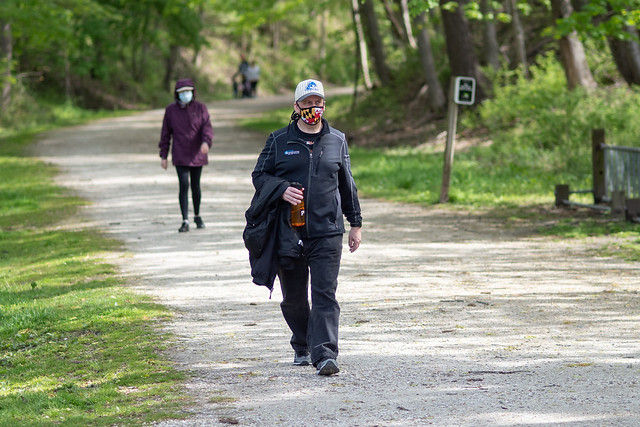 people wearing masks and social distancing on an outdoor path