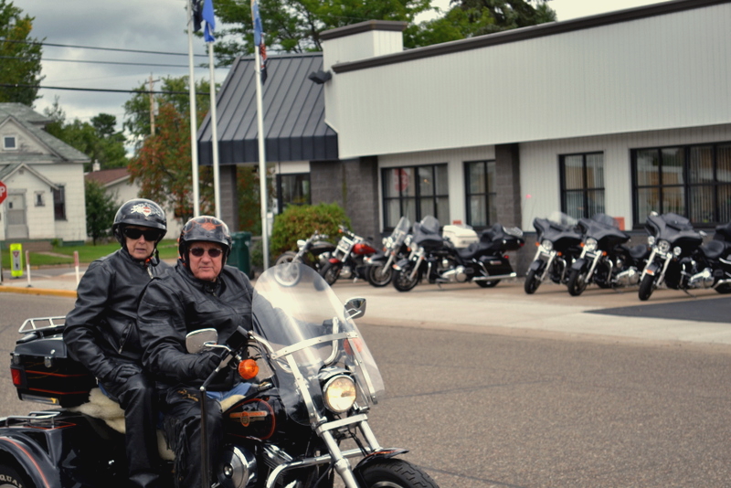 Two bikers riding a Harley in front of the Harley Soma Avenue Plant in Tomahawk.