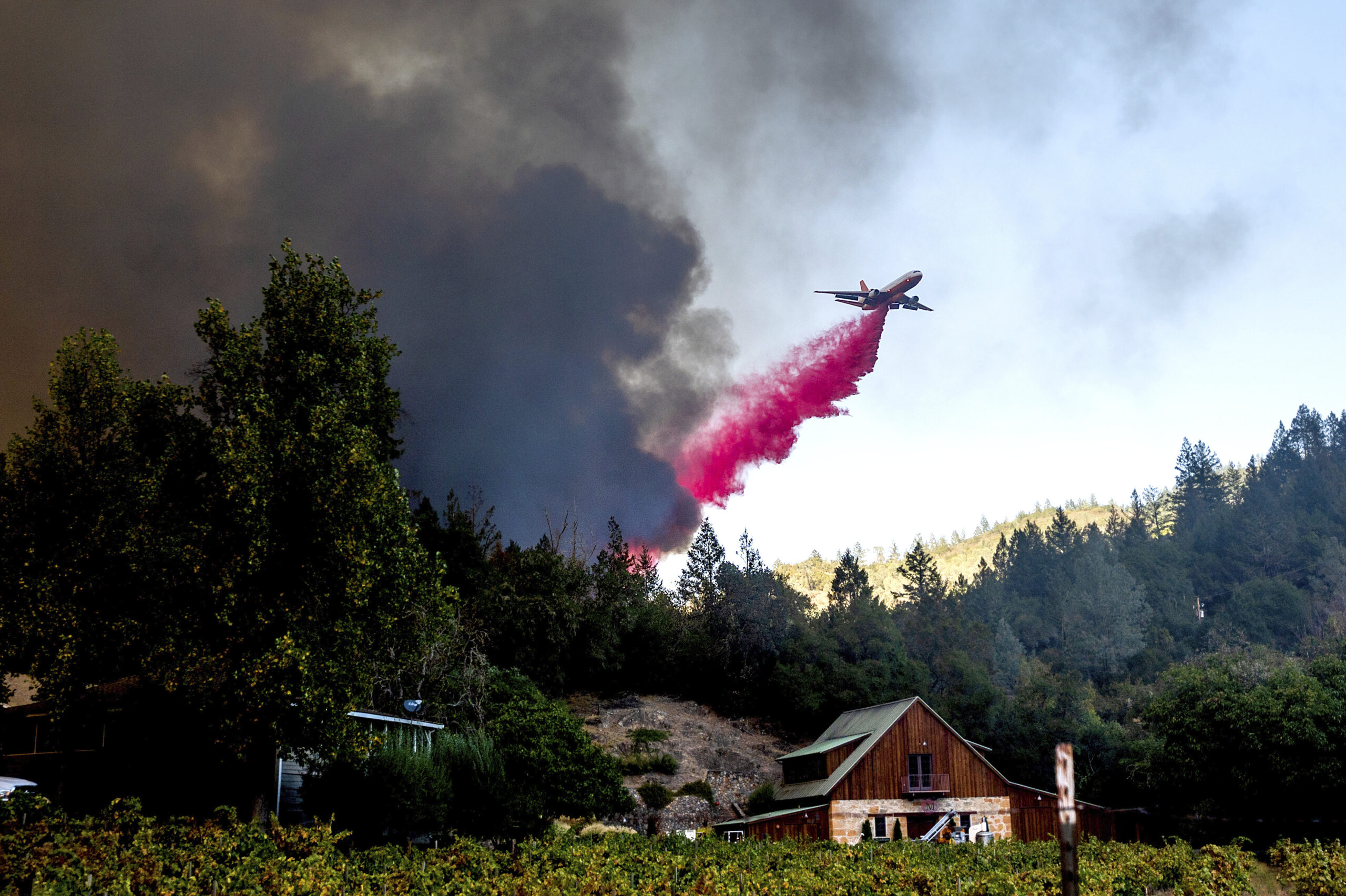 An airplane drops retardant on forest fire