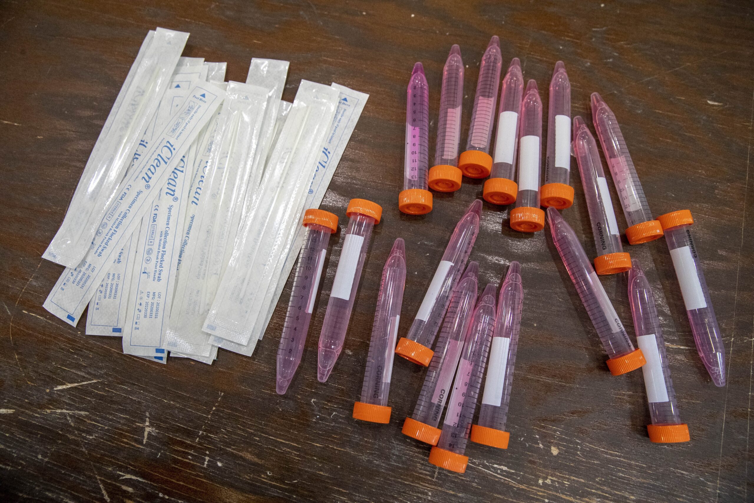Test swabs and specimen tubes sit on a table at a COVID-19 testing site