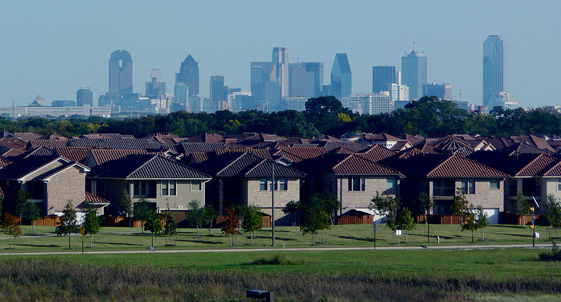 row of similar suburban houses, city skyline in background