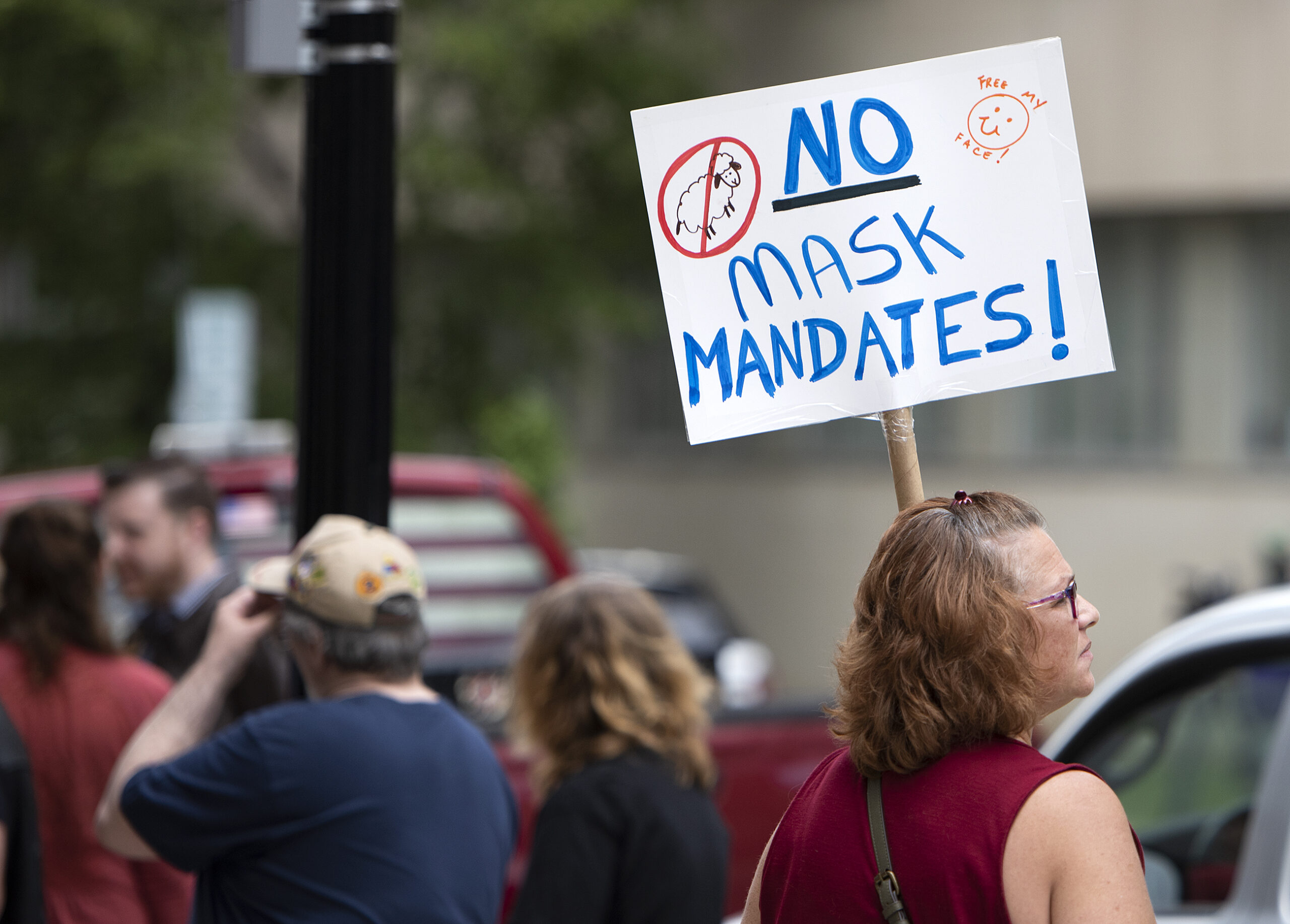 A woman's sign says "no mask mandates!"