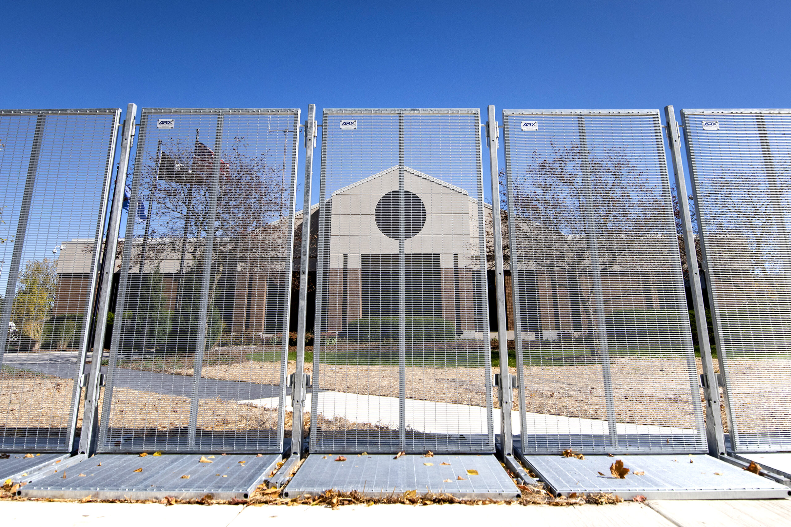 A large metal fence stands tall in front of the police department building