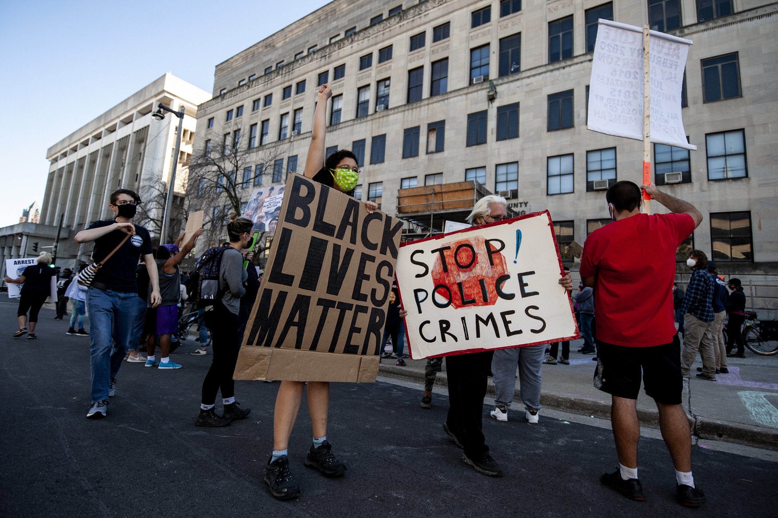 people hold signs that say "black lives matter" and "stop police crimes"