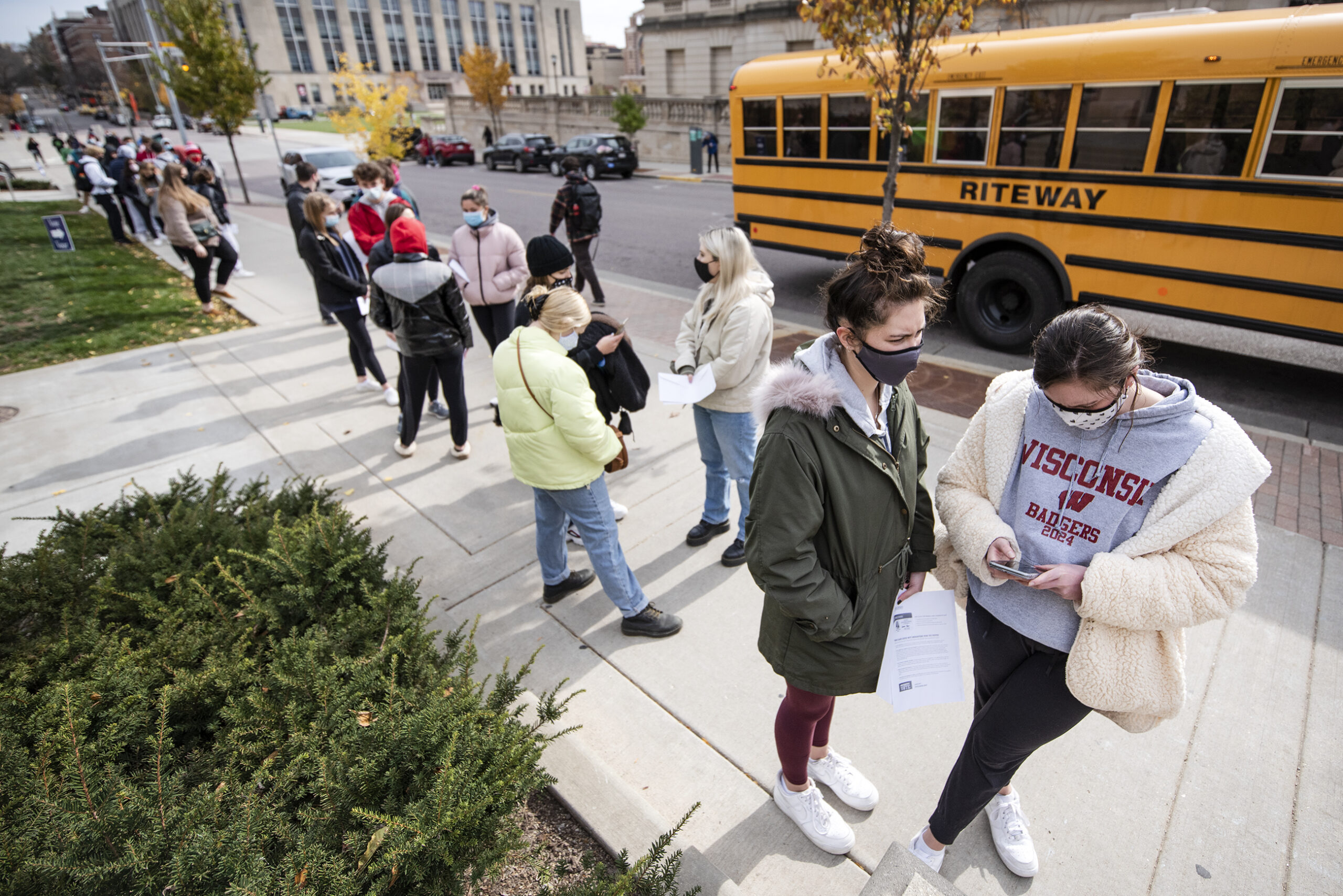 Voters hold their ballots as they wait in line to vote early