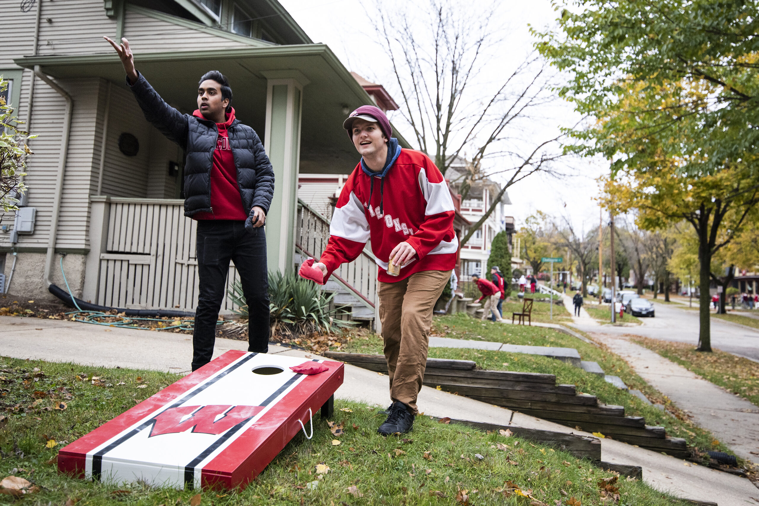 two students throw bags outdoors on a lawn