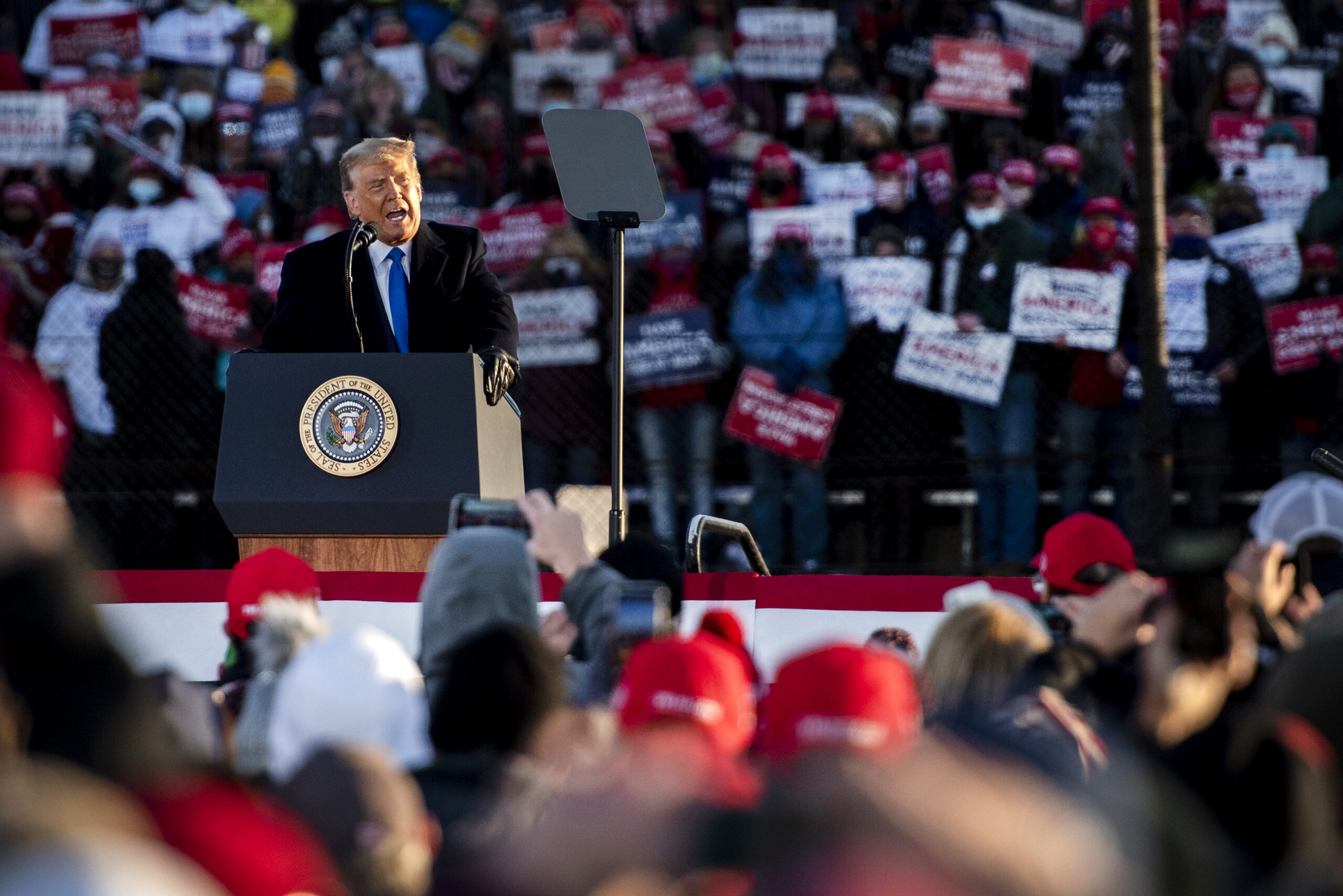 Pres. Trump speaks to a crowd of supporters gathered in front of him and behind him in bleachers