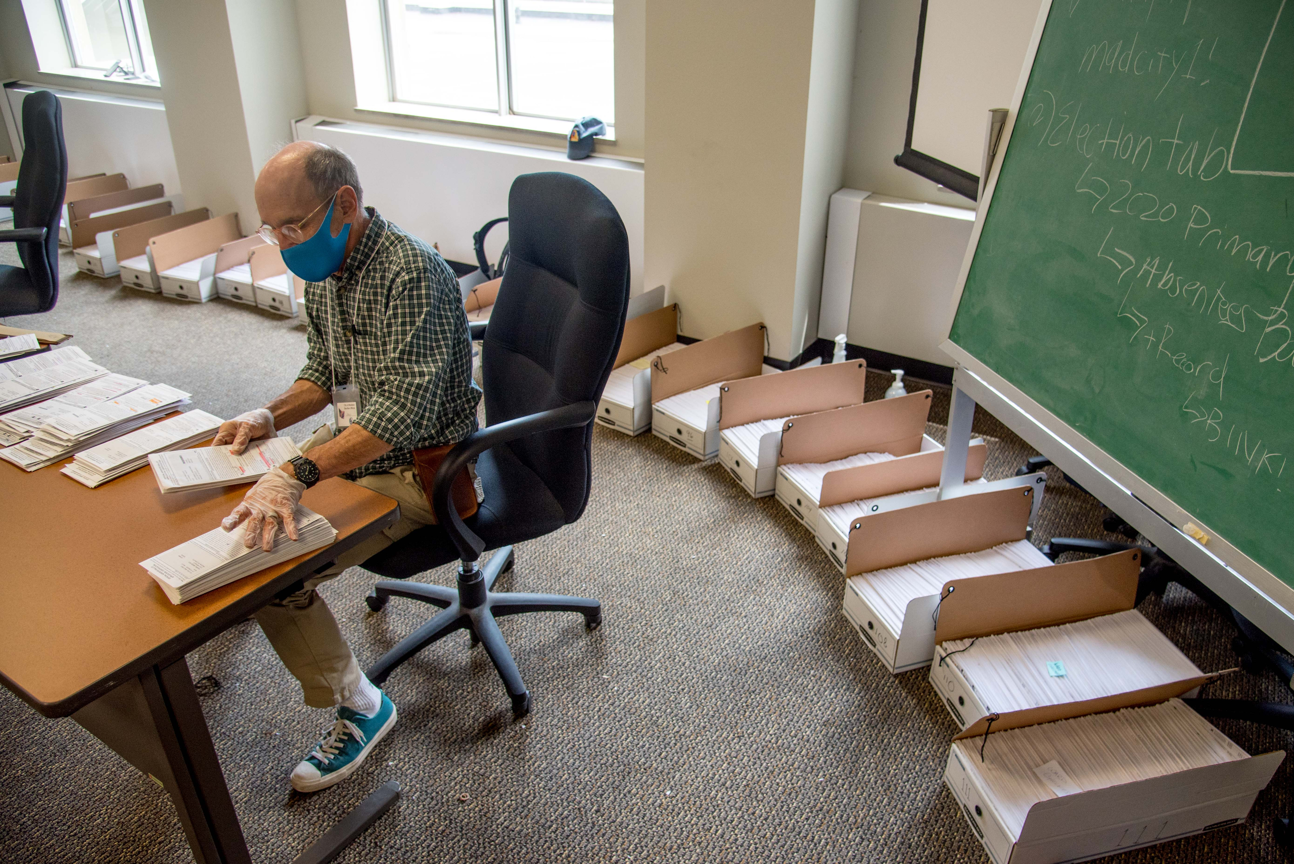 Election official Lenny Black alphabetizes returned absentee ballots in the City-County Building in Madison