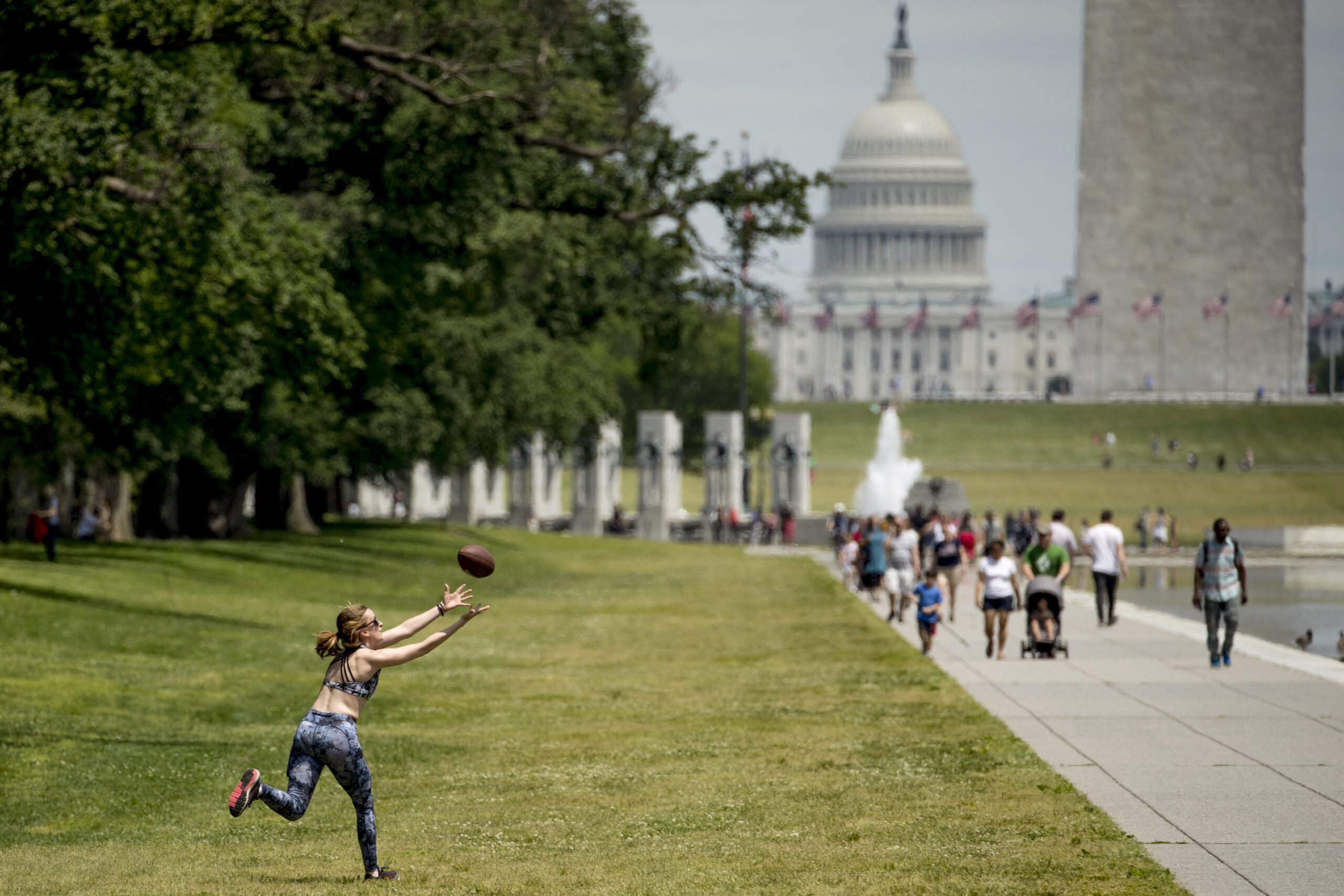 A woman catching a football in front of U.S. Capitol