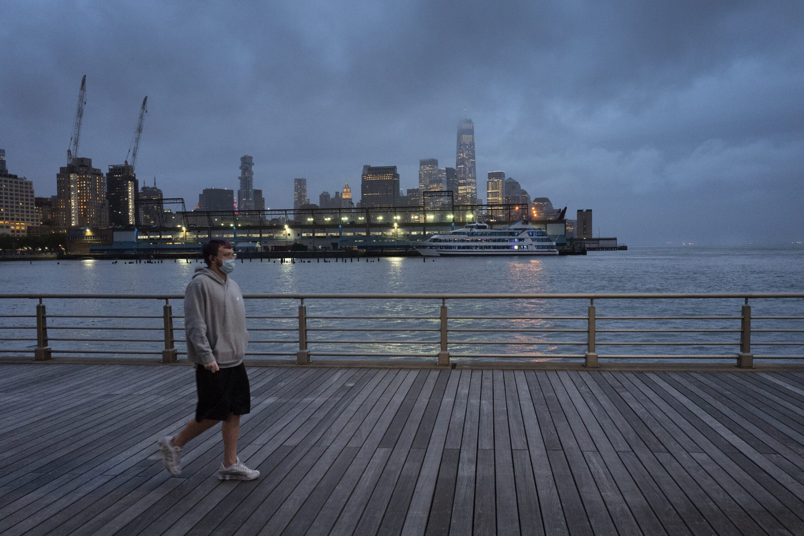 a man wears a face mask as he walks on Pier 45 in Hudson River Park in New York