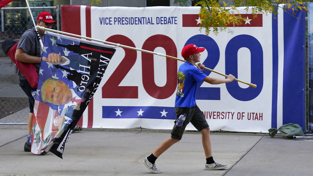 A Trump supporter carries a flag outside the presidential debate venue
