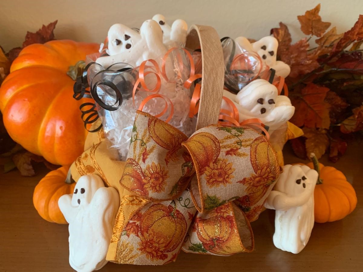 A halloween-themed, decorative basket display with the meringue ghosts poking out.