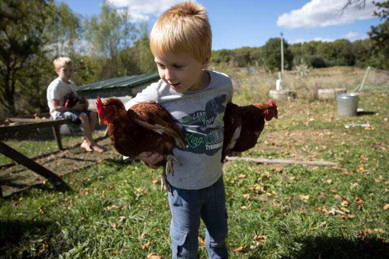 Matthias and Sterling Millar hold chickens outside their house