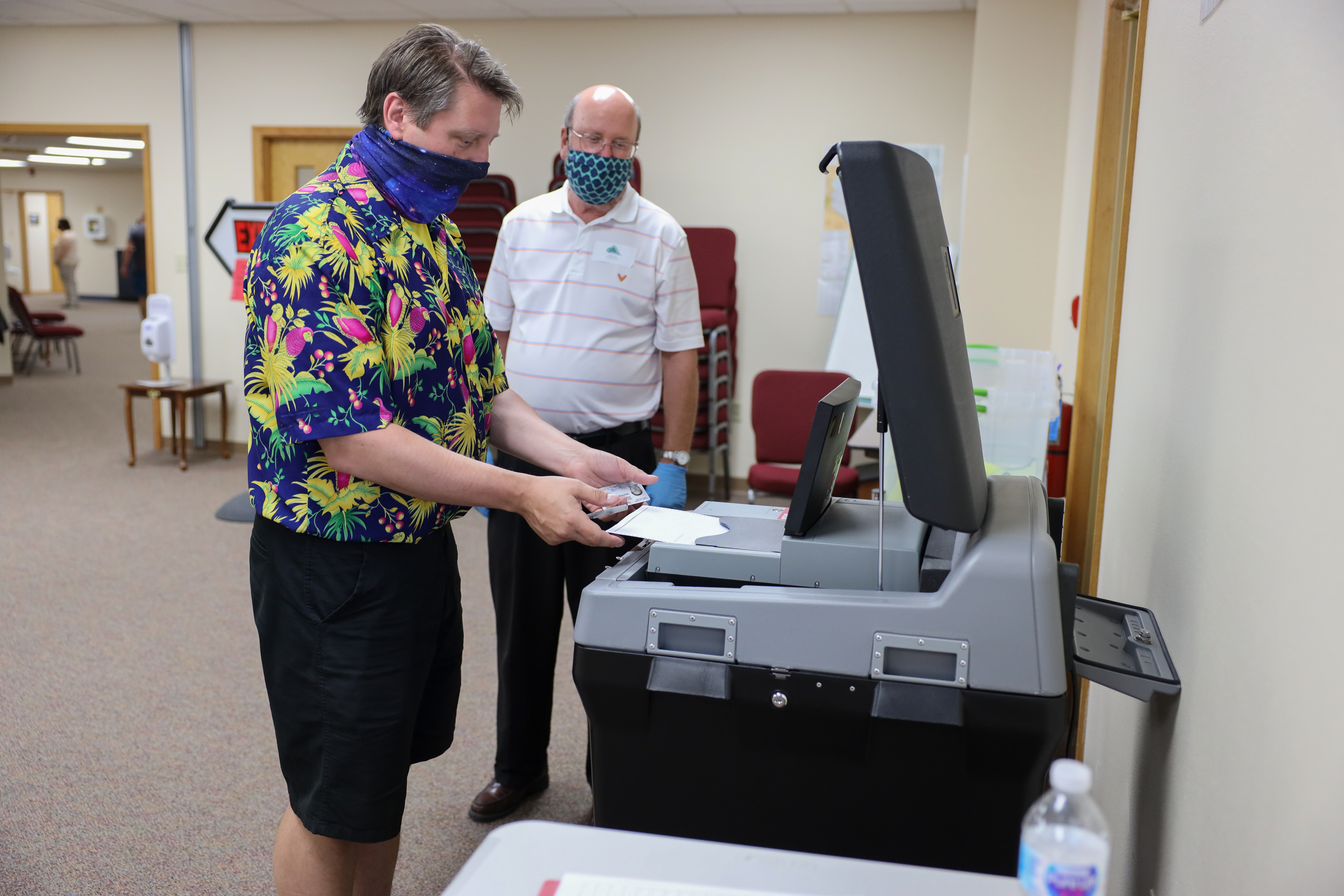 Kevin Mineau inserts his ballot into the DS200 vote-counting machine during the partisan primary