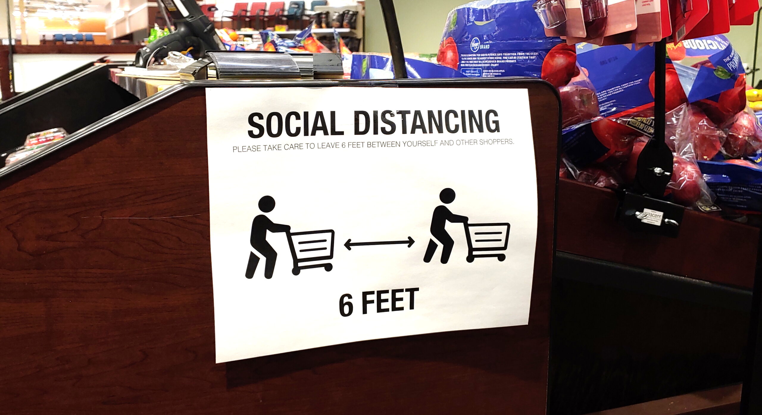 A store sign recommends social distancing