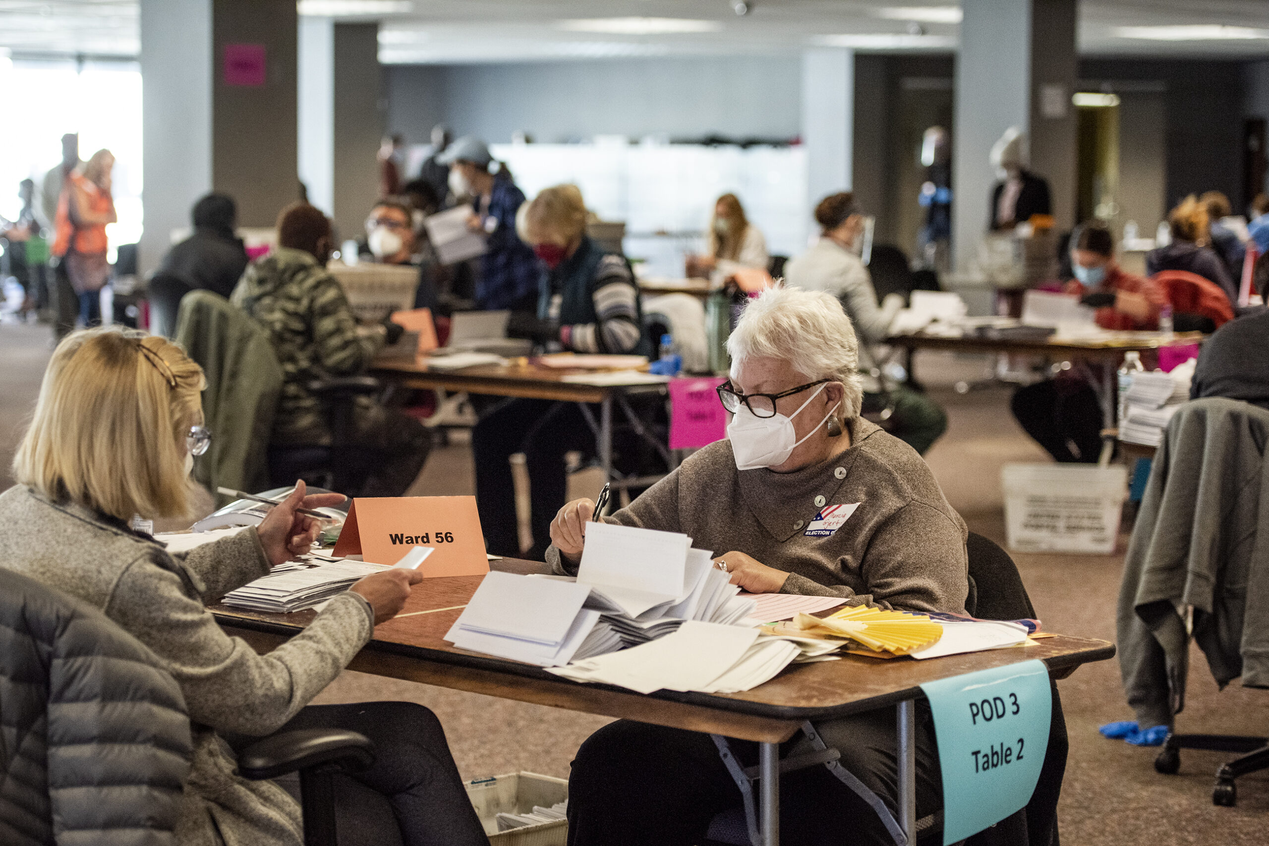 two workers sit at a table and sort ballots