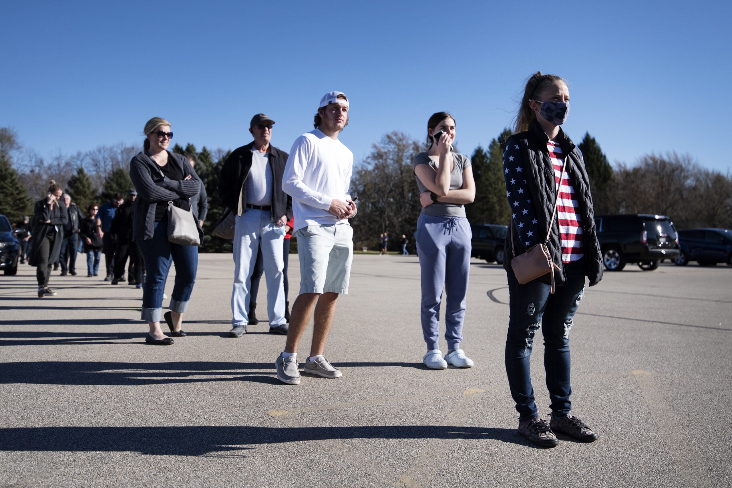 A woman in a U.S. flag pattered shirt stands in a line outside