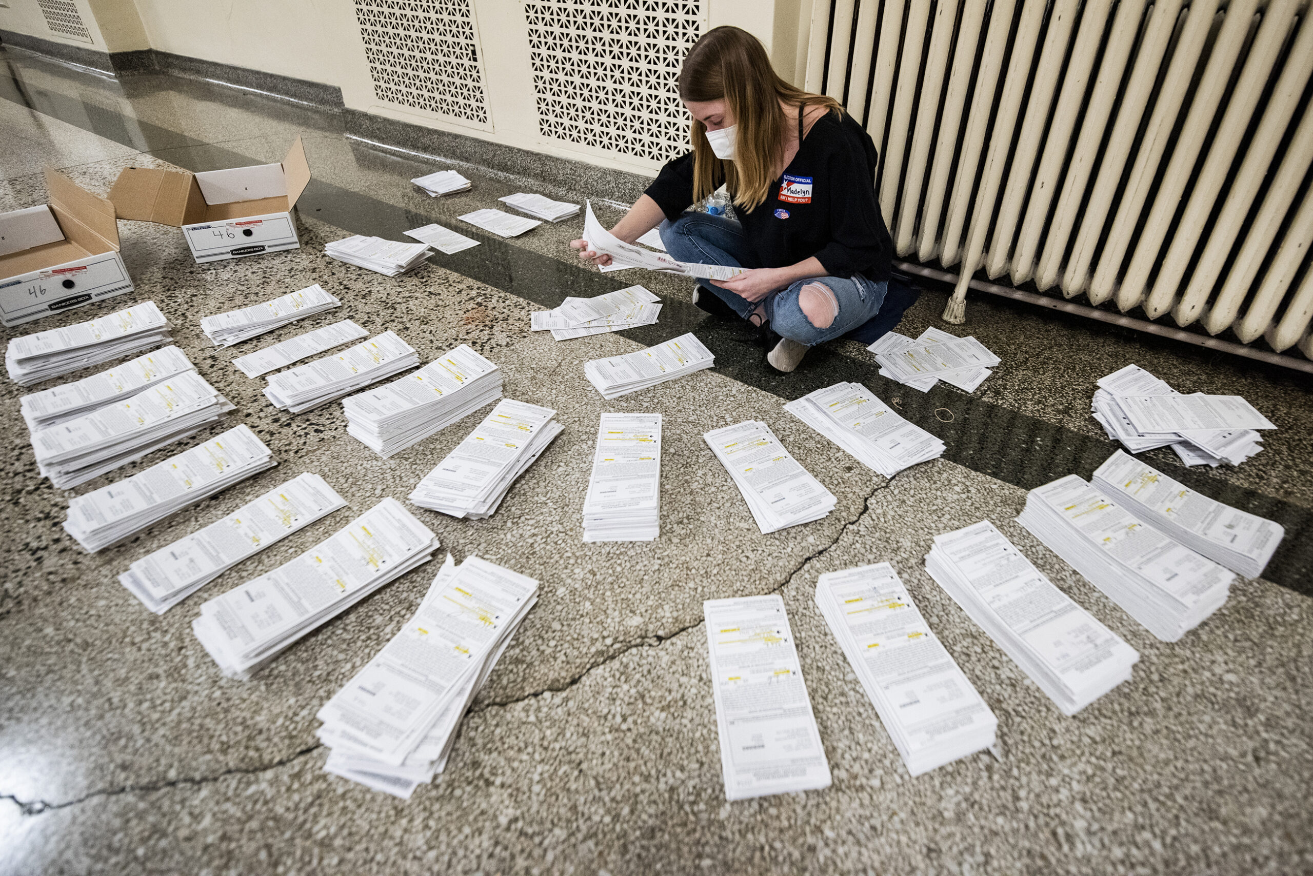 ballot envelopes surround a worker who sits on the floor