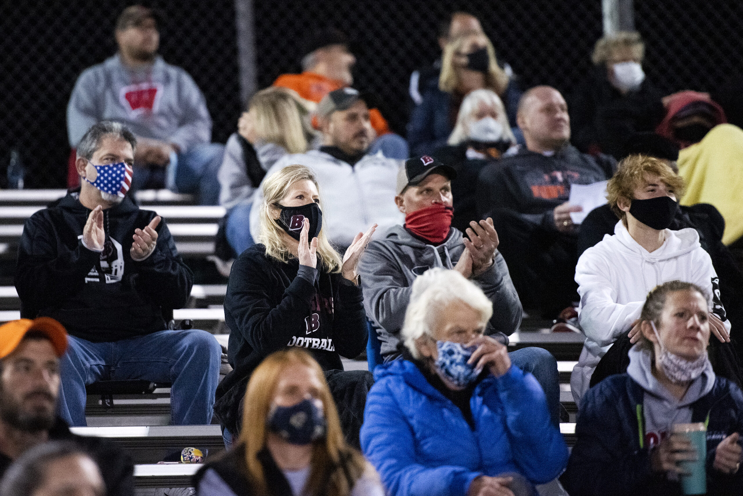 fans in face masks applaud from the bleachers