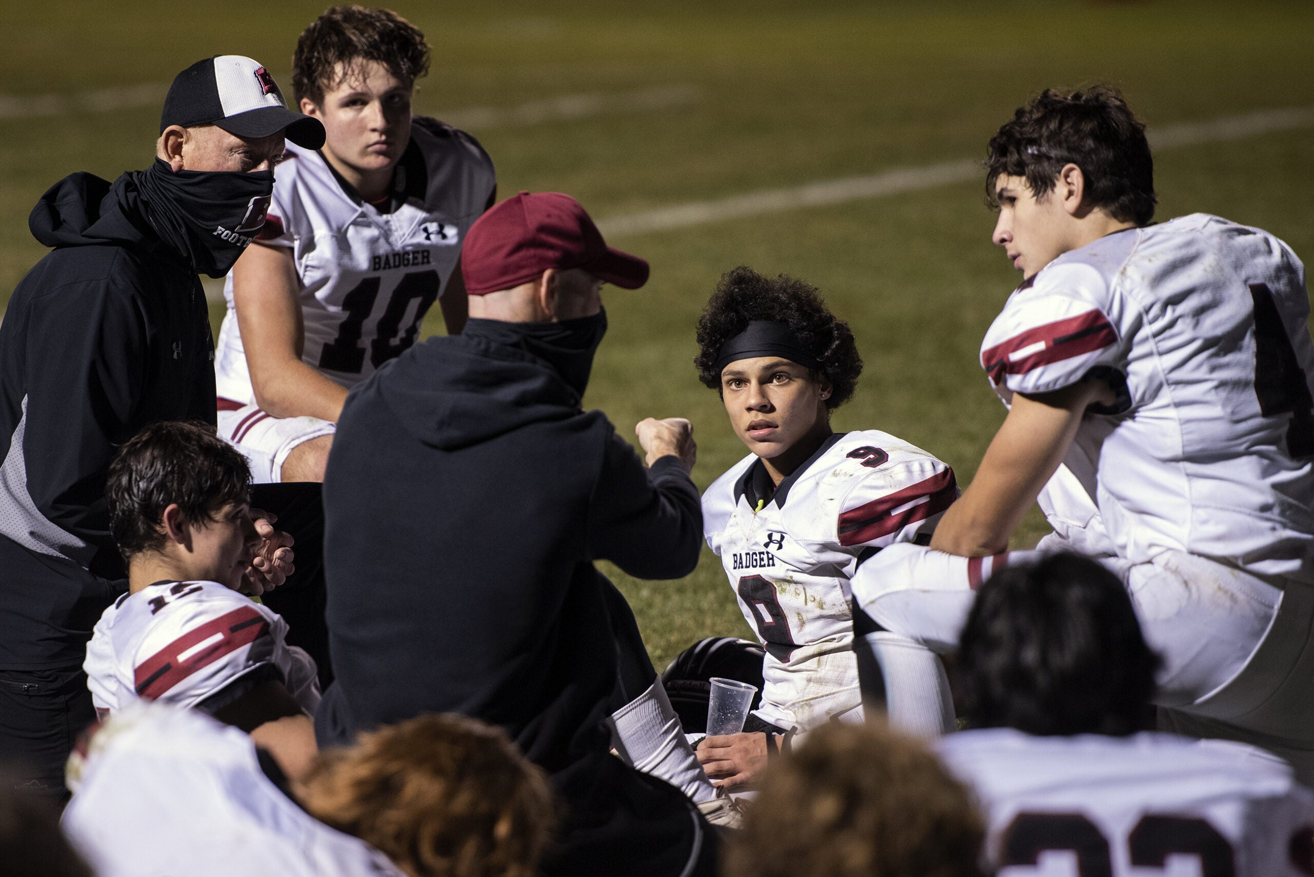 football players gather on the field during halftime and speak to coaches